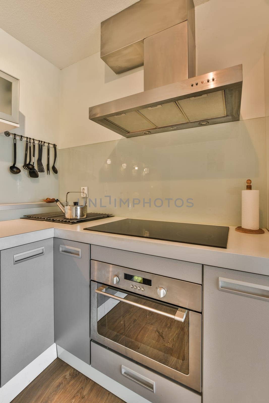 a modern kitchen with wood flooring and stainless steel appliances on the wall above the range hood in an apartment