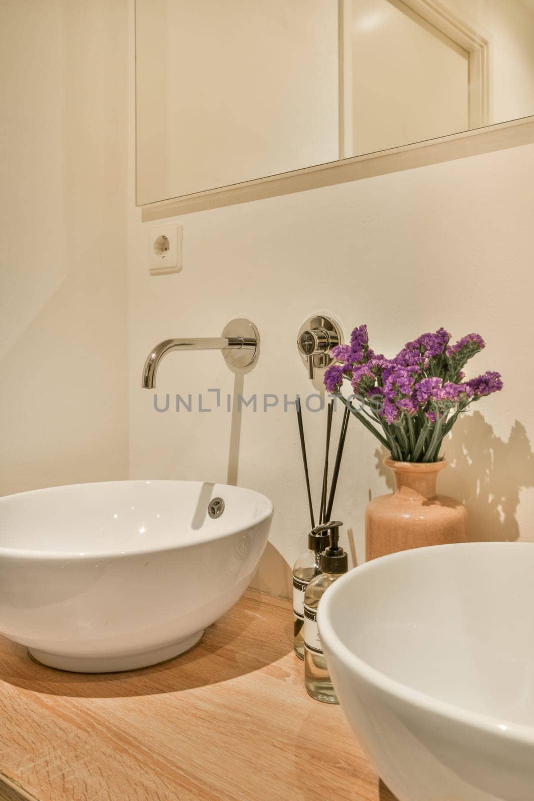 a bathroom with two sinks and flowers in the sink basin is next to the mirror on the wall behind it