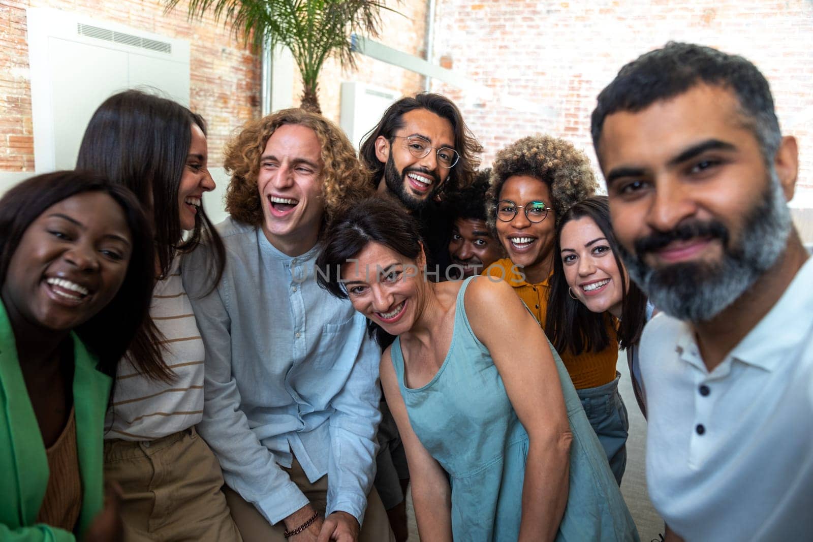 Happy multiracial group of coworkers take selfie together in the office. Lifestyle and friendship concept.