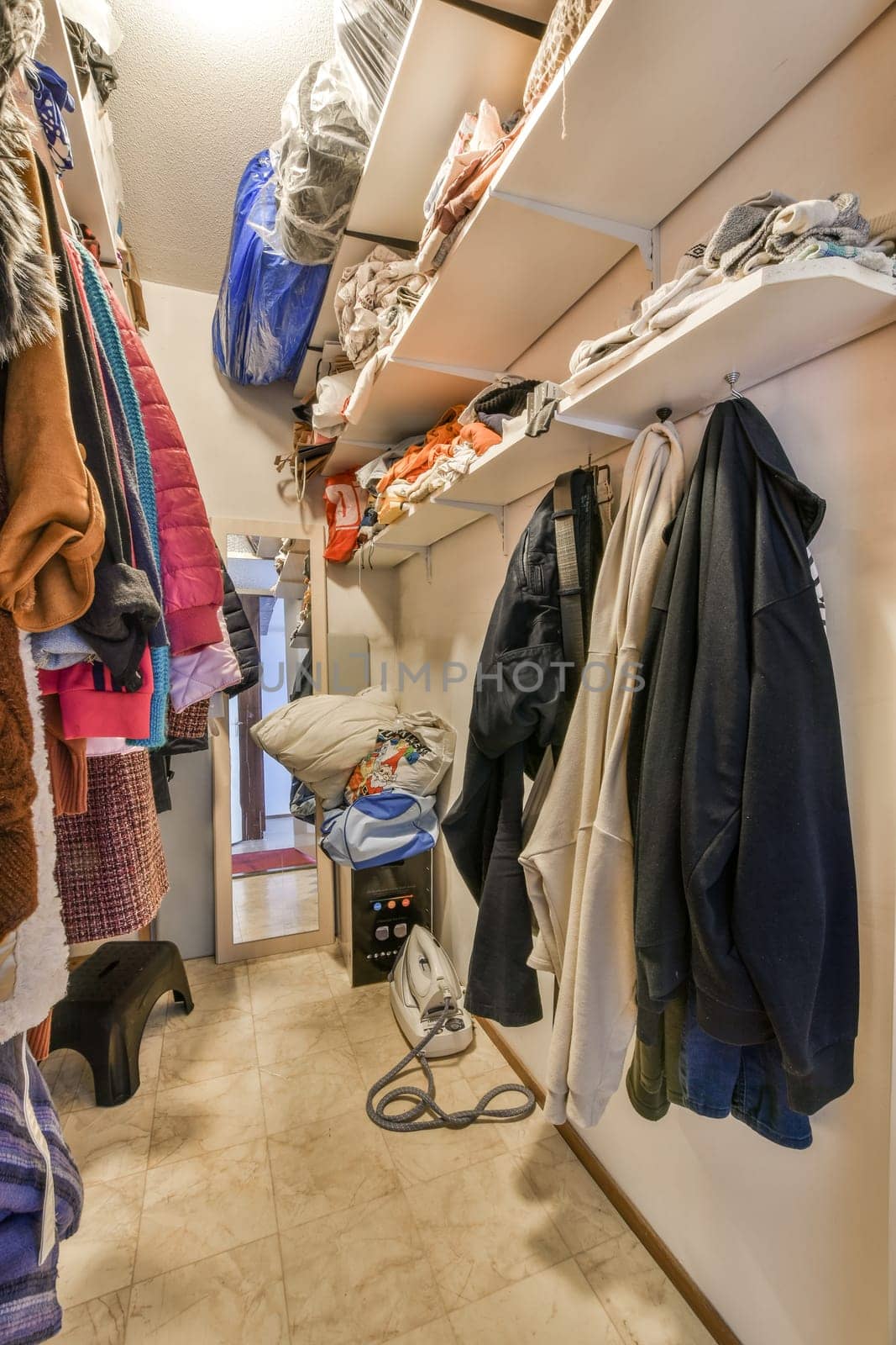 the inside of a closet with clothes hanging on hooks, and other items in storage space around it to be used