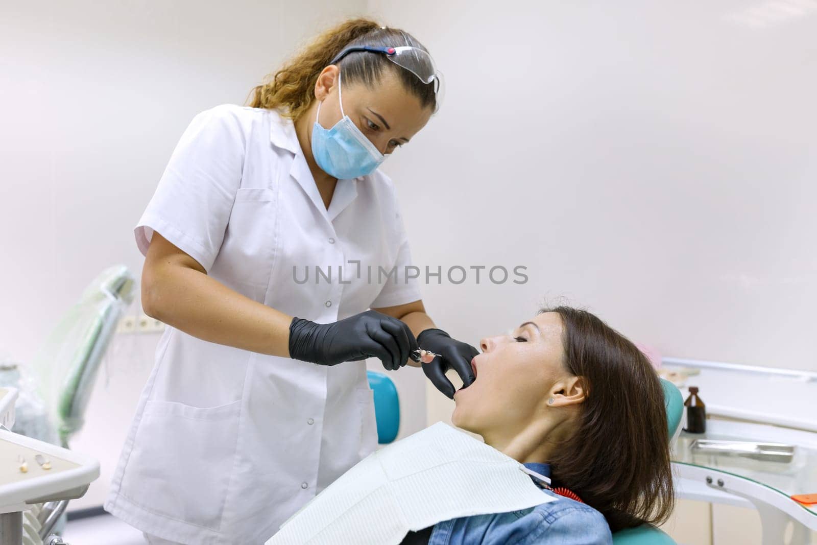Partial denture, mature woman patient sitting in dental chair, doctor dentist doing dental prosthesis. Healthcare, medical and dentistry concept