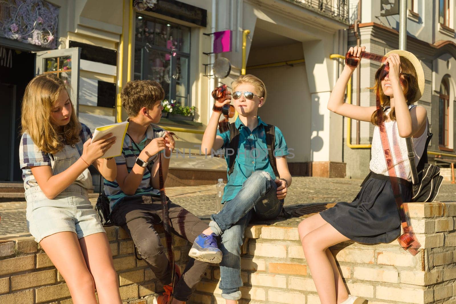 Teenagers with interest and surprise watching film photo negatives, city street background by VH-studio