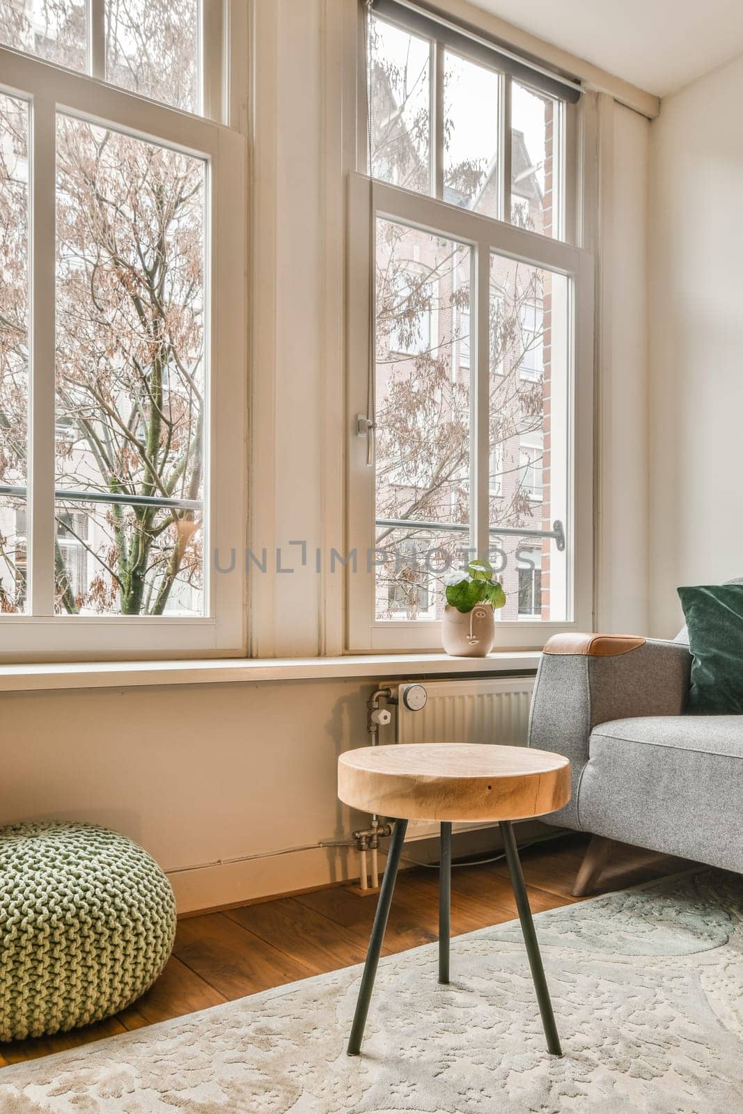 a living room with a couch, coffee table and two large windows that look out onto the street in winter