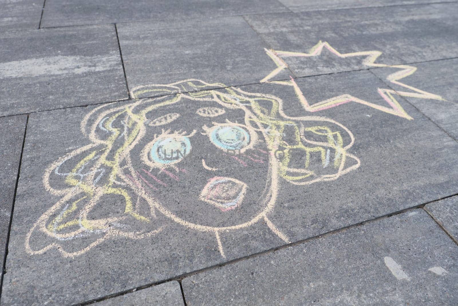 Abstract pop art woman face, picture written on gray sidewalk in crayons, top view