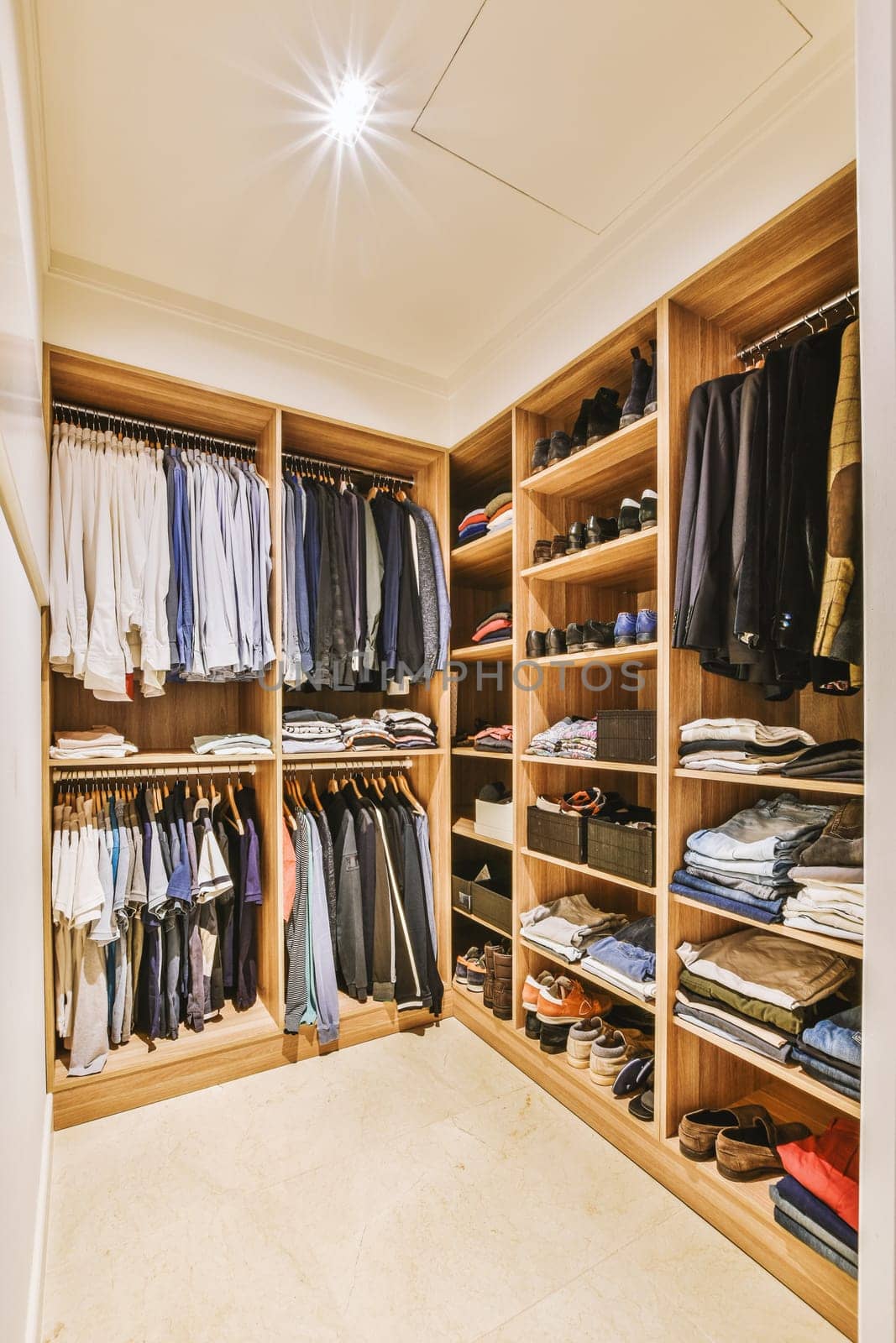 a walk in closet with wooden shelves and a ceiling by casamedia