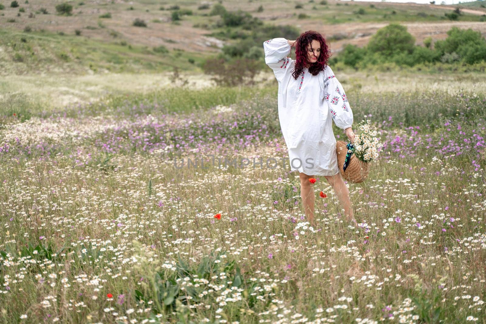 Chamomile woman. Happy curly woman in a chamomile field, dressed in a white dress