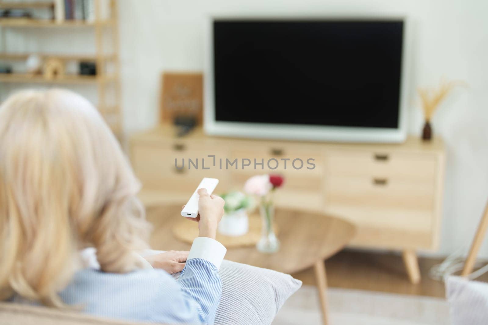 Portrait of a beautiful Asian woman relaxing at home watching television.