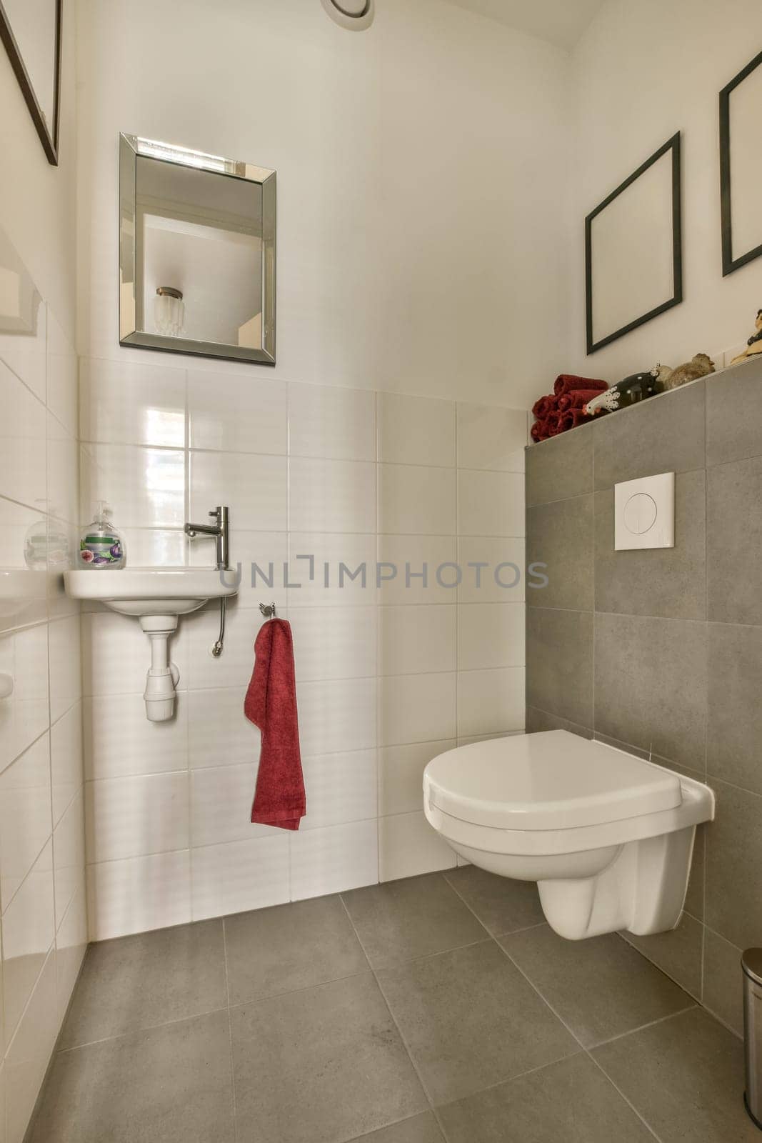 a bathroom with a toilet, sink and mirror hanging on the wall above it is a red towel next to the toilet