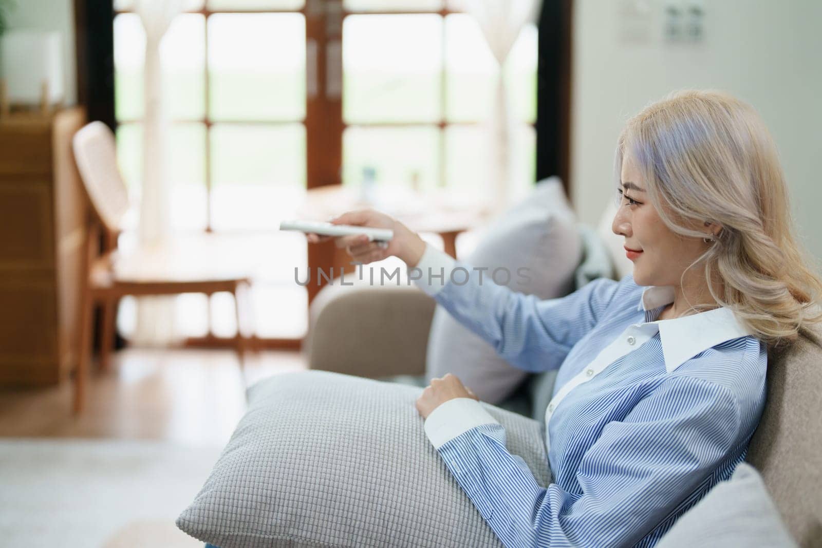 Portrait of a beautiful Asian woman relaxing at home watching television by Manastrong