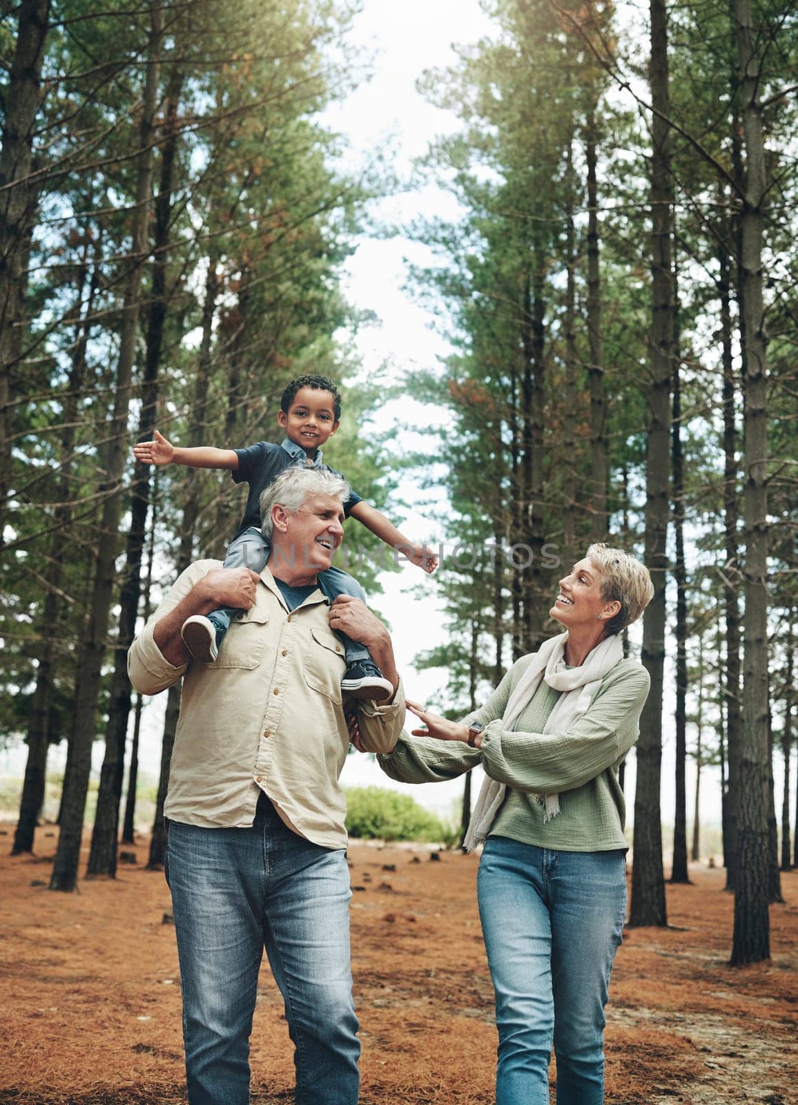 Hike, nature and children with senior foster parents and their adopted son walking on a sand path through the tress. Family, hiking and kids with an elderly man, woman and boy taking a walk outside.