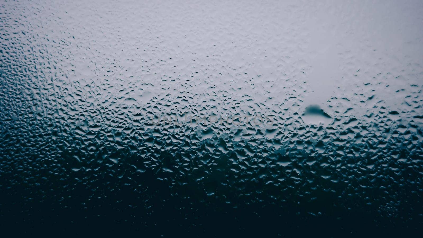 Waterdrops on glass window after raining with bright light from background.