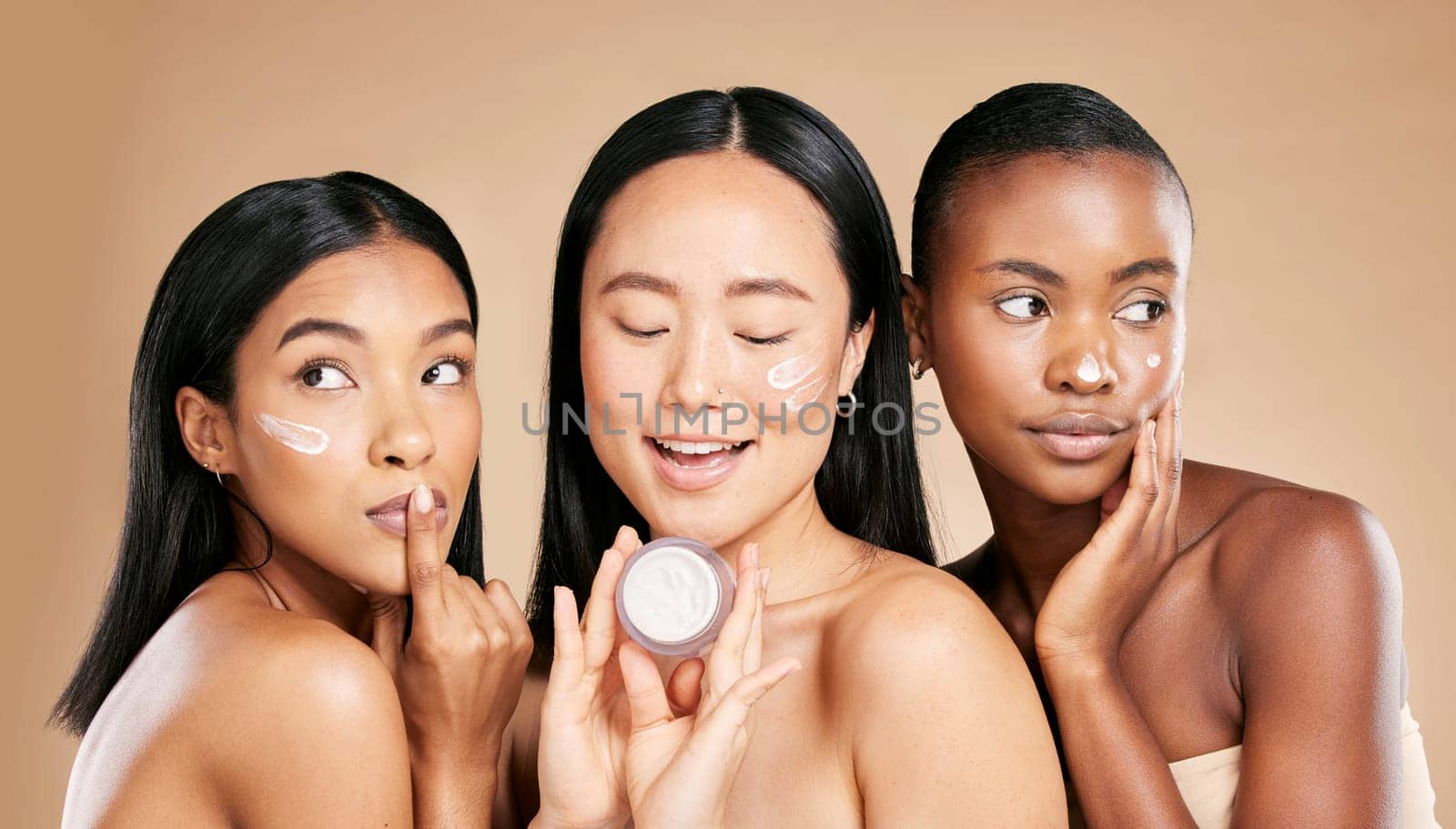 Skincare, women and face cream in studio for wellness, grooming and hygiene against brown background. Friends, beauty and lotion for girl group with different, facial and skin product while isolated by YuriArcurs