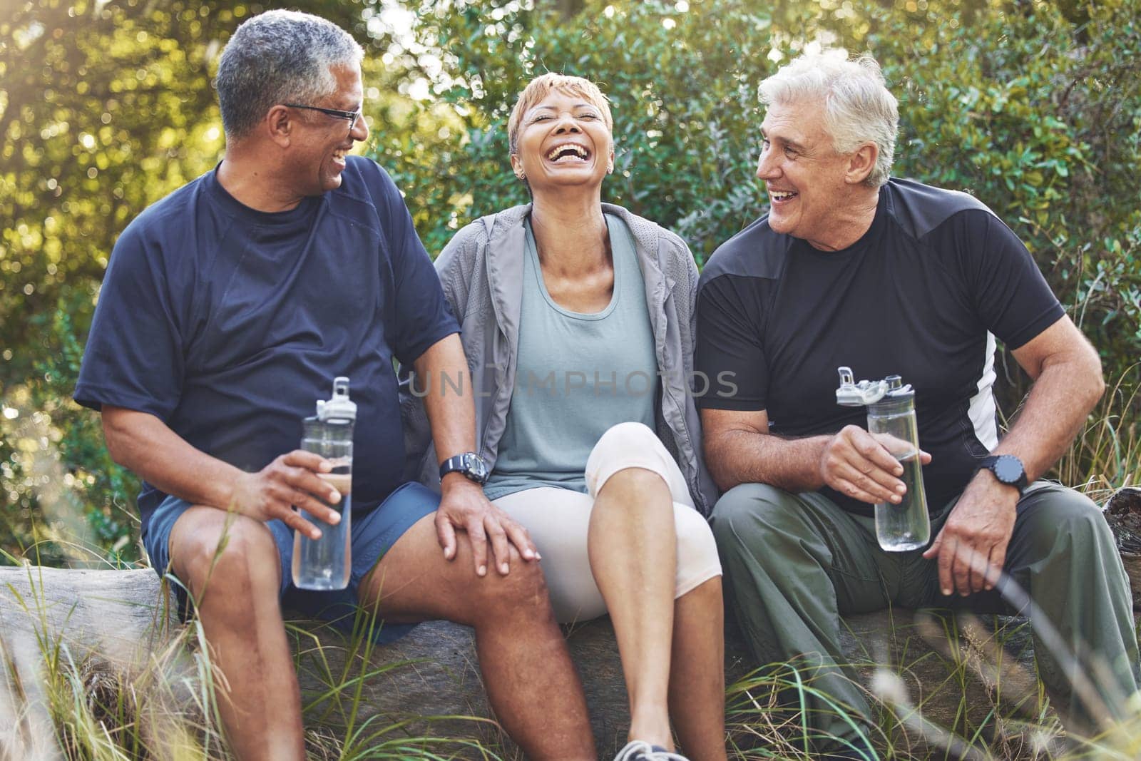 Nature, fitness and senior friends in conversation while sitting in the forest after hiking. Happiness, communication and elderly people talking, bonding and drinking water after outdoor exercise