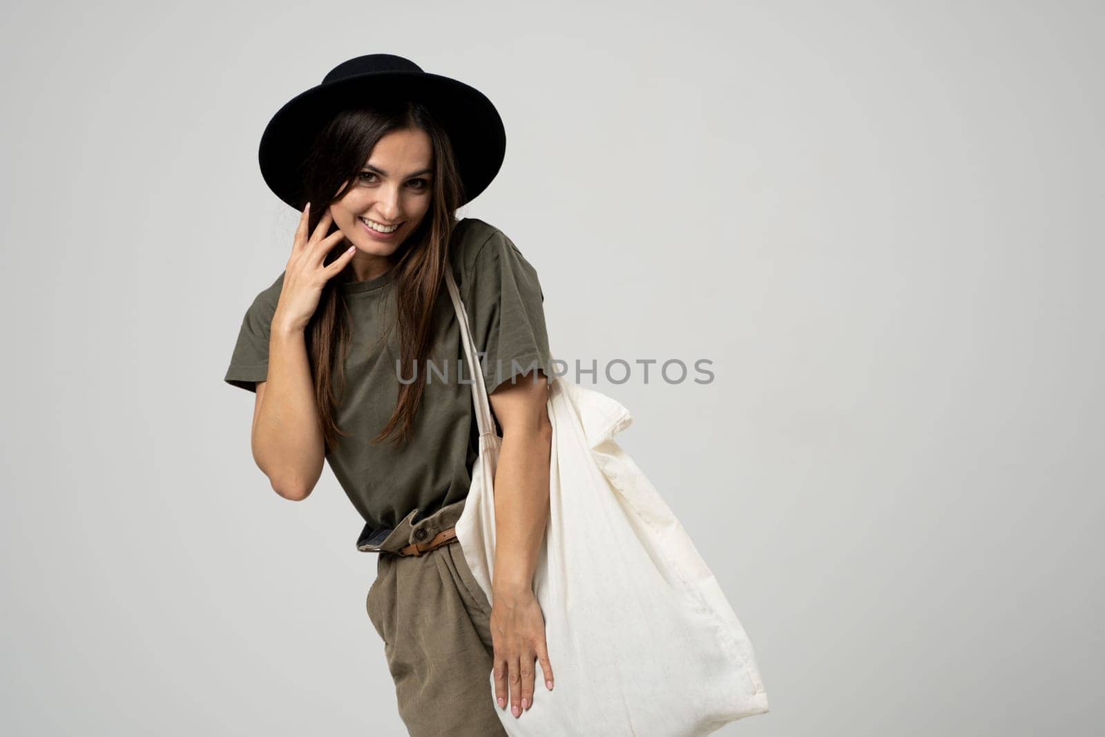 Happy beautiful brunette woman with white cotton bag in her hands. Girl holding textile grocery bag with vegetables. Zero waste concept. by vovsht