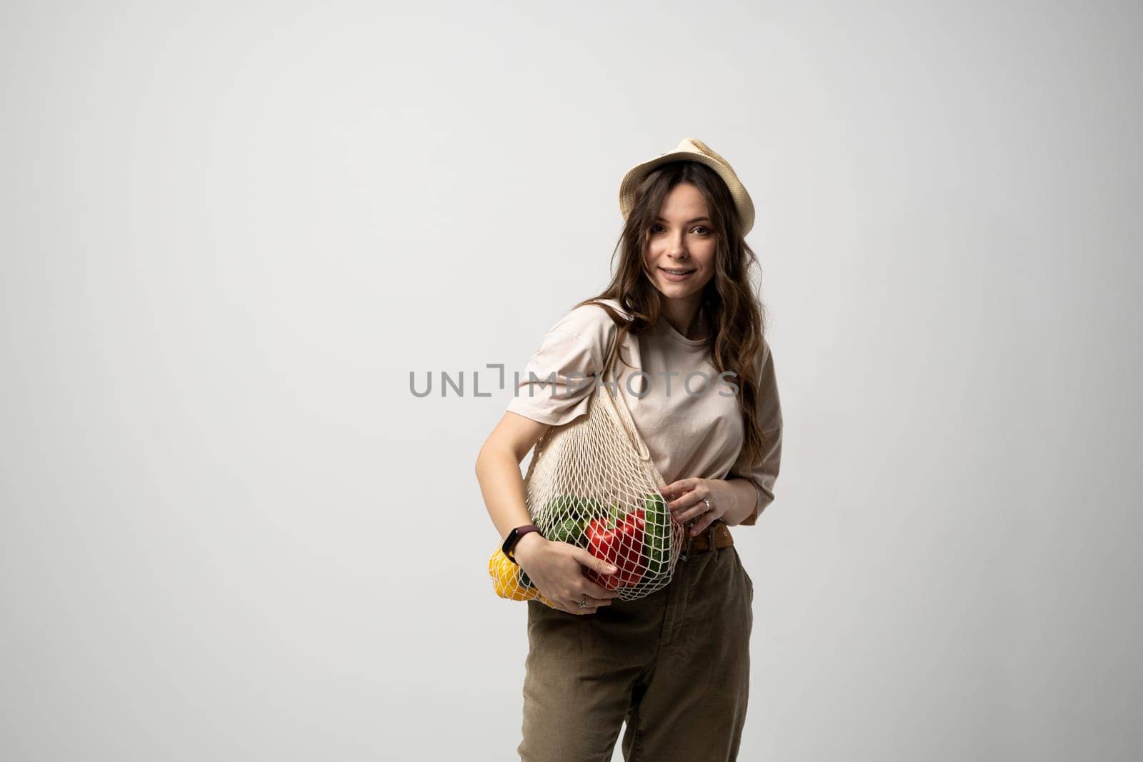 Zero waste concept with copy space. Woman holding a reusable mesh shopping bag with vegetables, products. Eco friendly mesh shopper. Zero waste, plastic free concept