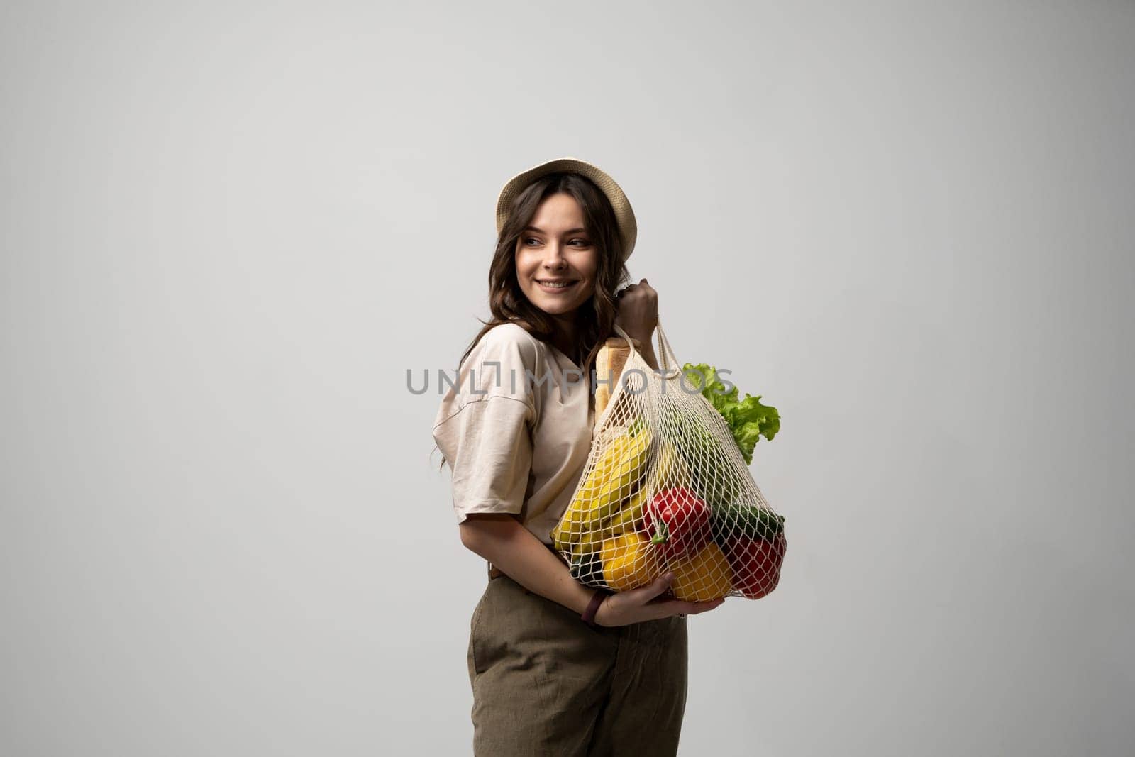 Woman holding mesh grocery bag with vegetables. Concept of no plastic. Zero waste, plastic free. Eco friendly concept. Sustainable lifestyle. by vovsht
