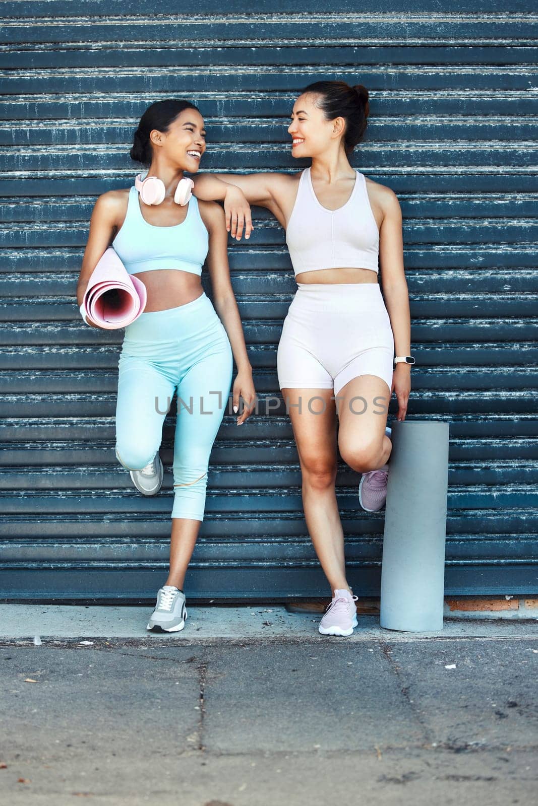 Fitness women, friends and yoga mat practice looking fit, slim and happy about exercise, training and workout standing against an urban background. Females together for aerobics, health and wellness by YuriArcurs
