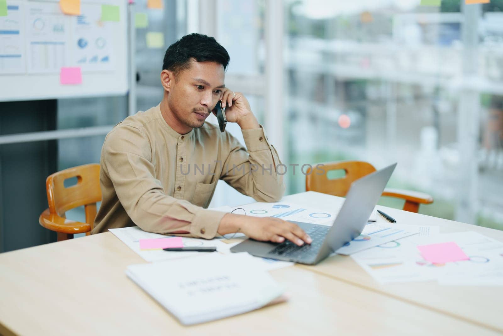 business owner or Asian male marketers are using business phones and computers to do office work.