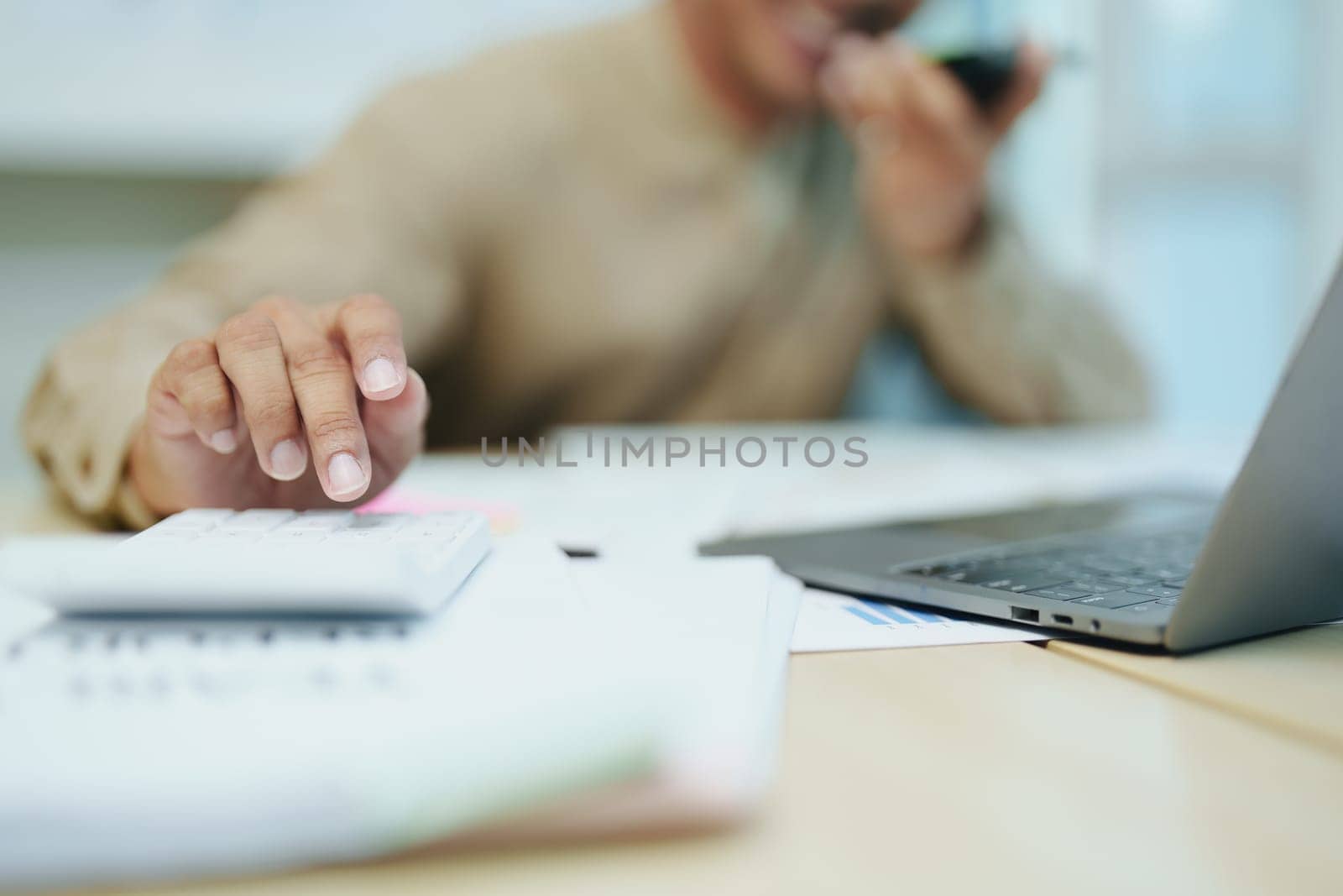 business owner or Asian male marketers are using business phones, calculator and computers to do office work.