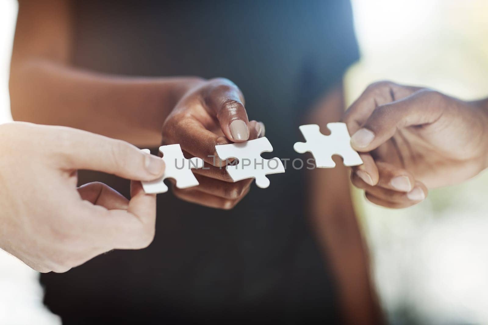 There is no solution greater than teamwork. Cropped shot of a work group connecting pieces of a puzzle. by YuriArcurs