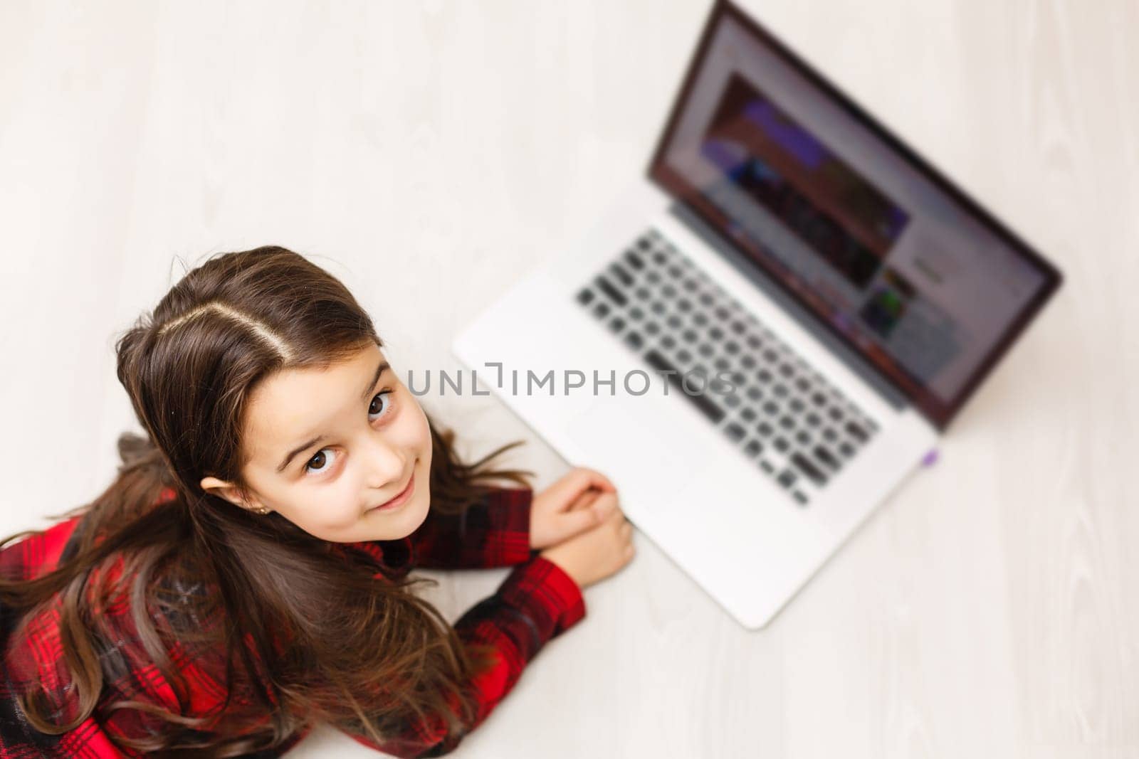 Top view of cute young girl using laptop by Andelov13