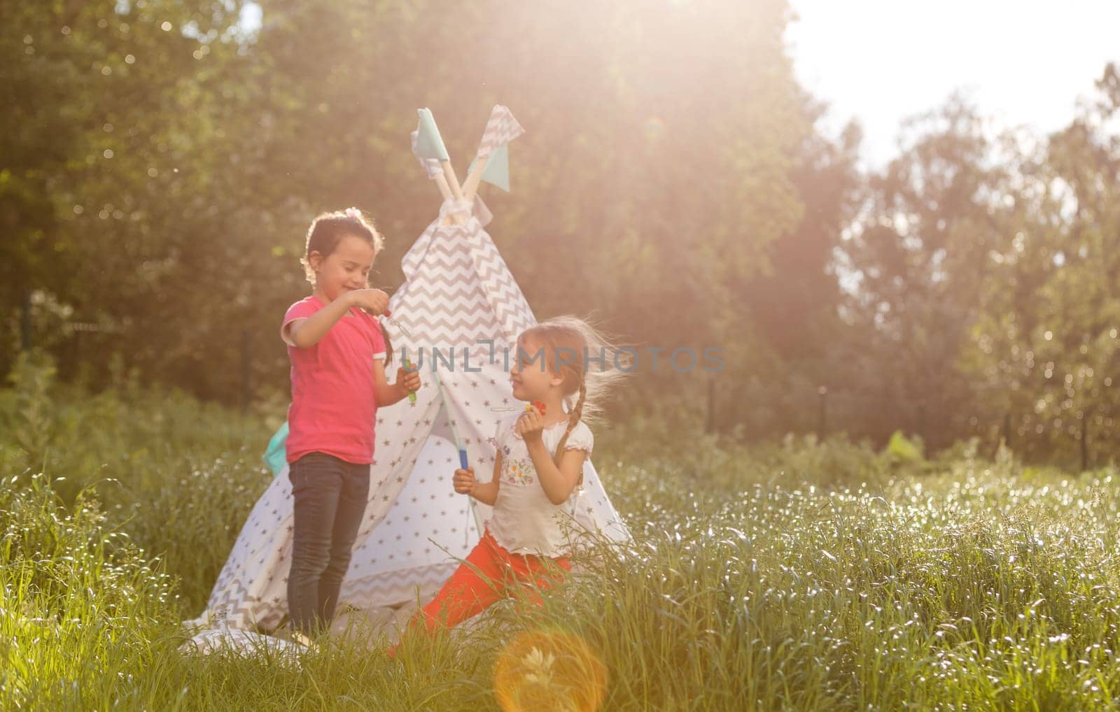Adorable little girls having fun playing outdoors on summer day.