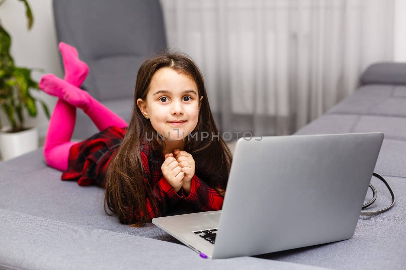Happy little girl at home working with a laptop by Andelov13