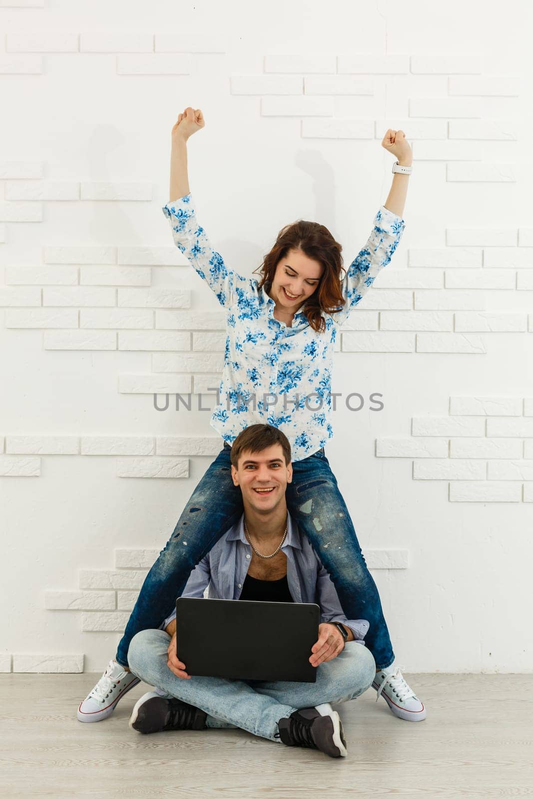 Portrait of happy young couple using laptop on gray background by Andelov13
