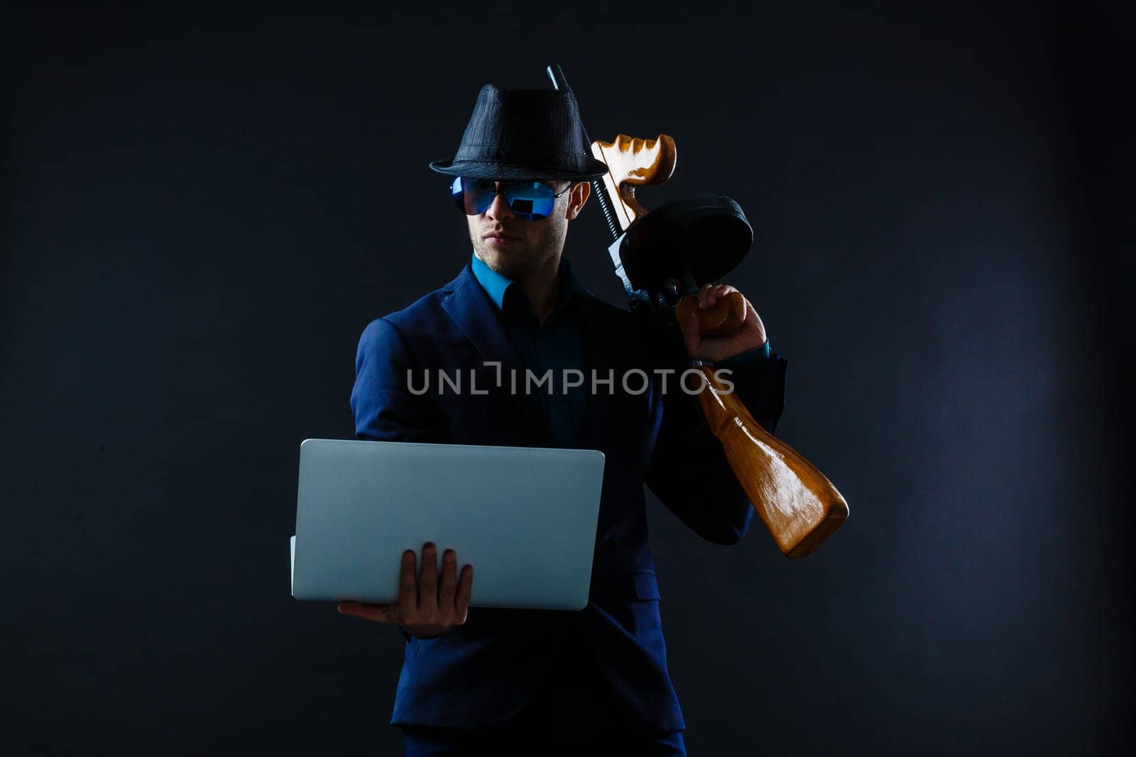 businessman in sunglasses with machine gun and laptop.