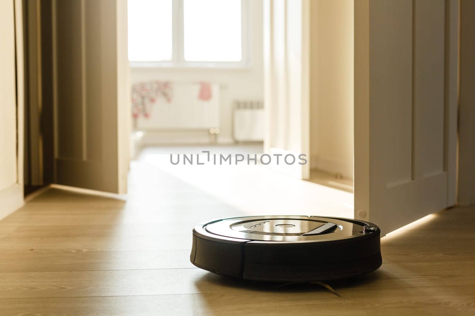 Robotic vacuum cleaner on laminate wood floor smart cleaning technology. Selective focus.