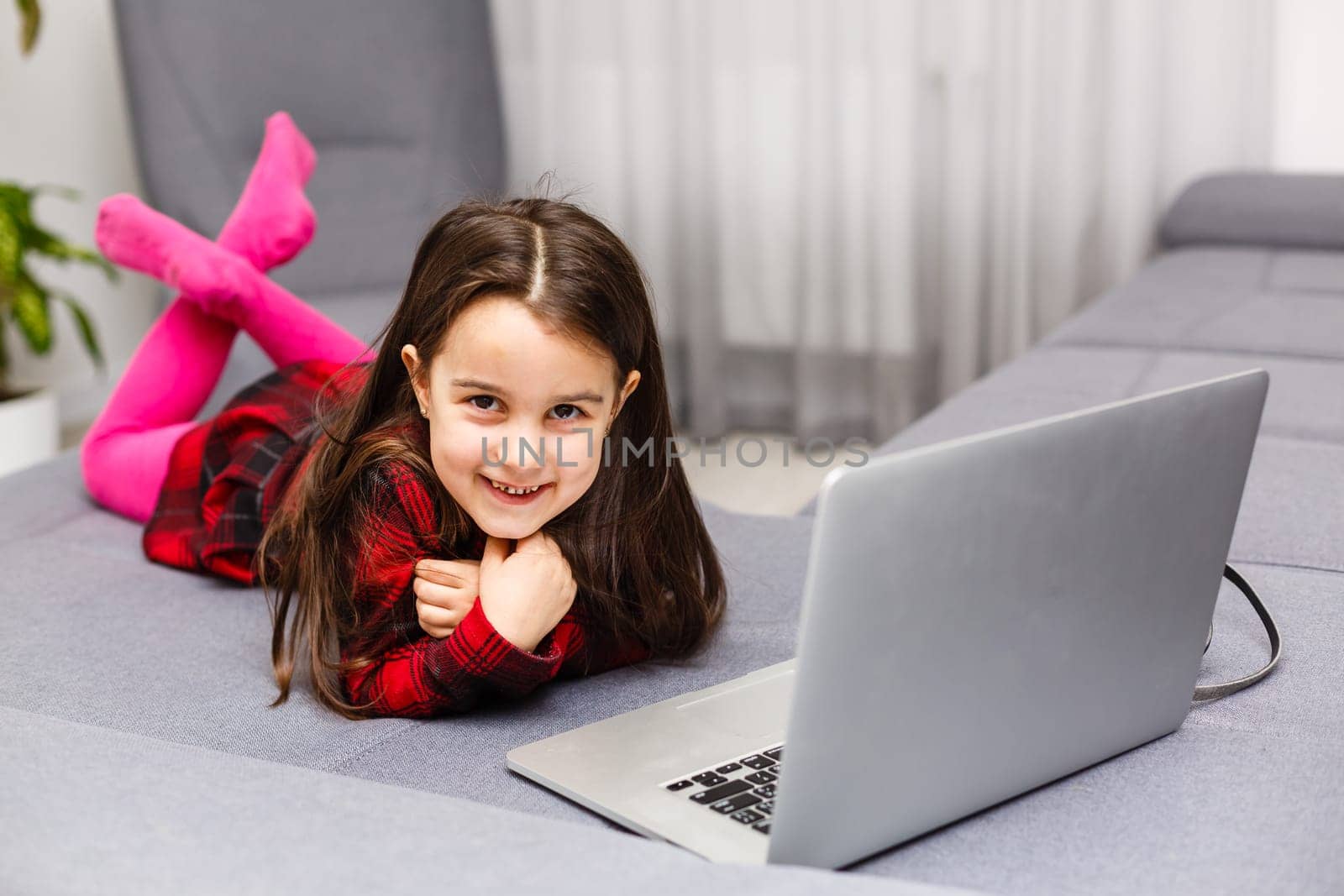 Happy little girl at home working with a laptop by Andelov13