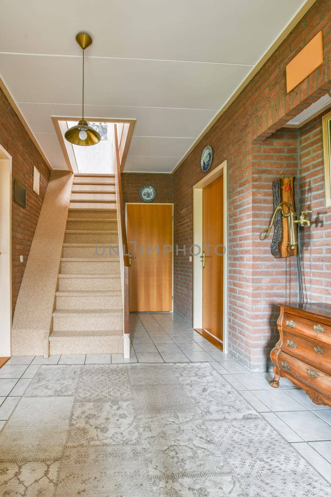 a hallway in a house with brick walls and white floor tiles on the wall, there is a staircase leading up to the second