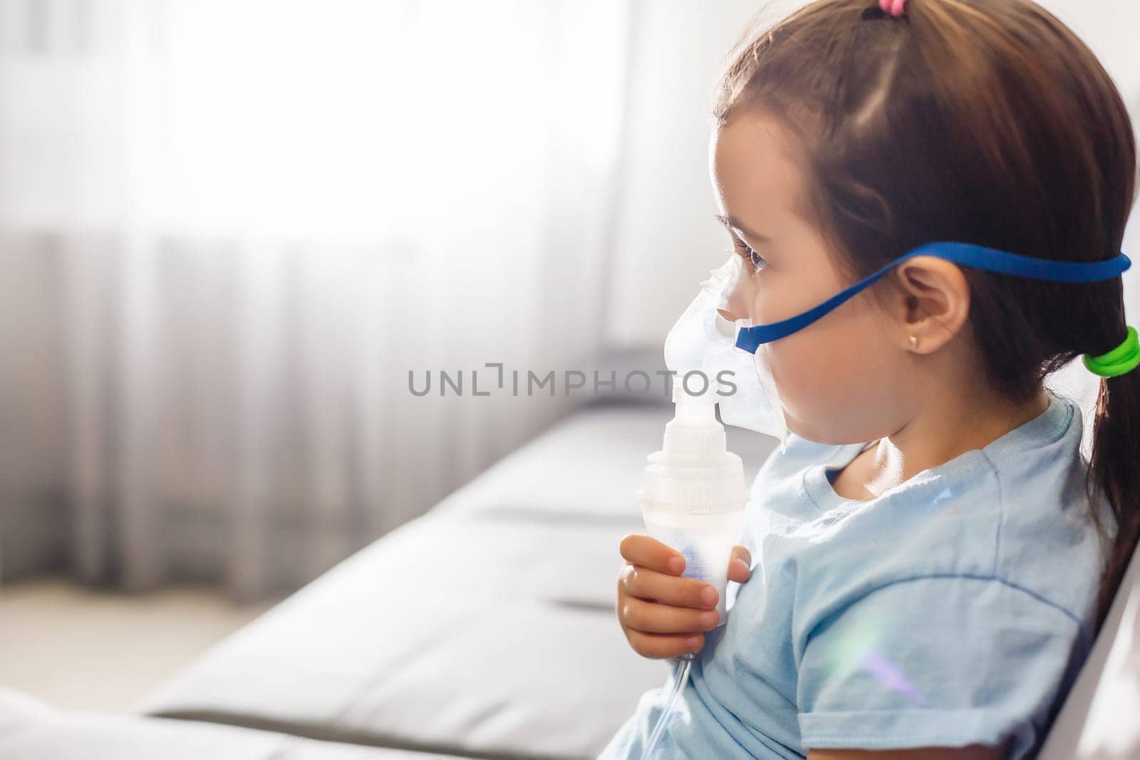 Little girl in a mask, treatments respiratory tract with a nebulizer at home by Andelov13