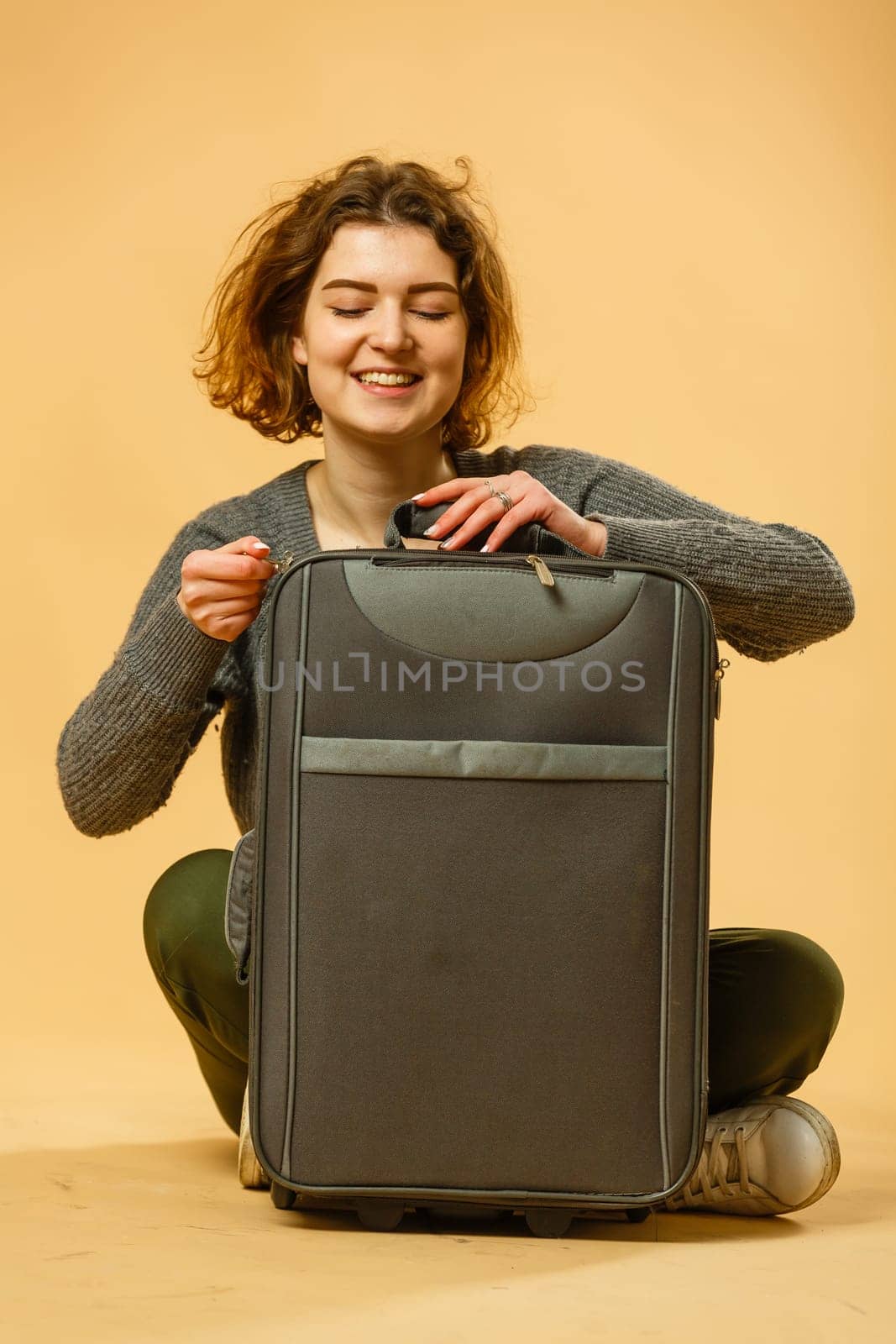 Woman traveler with suitcase on beige background by Andelov13