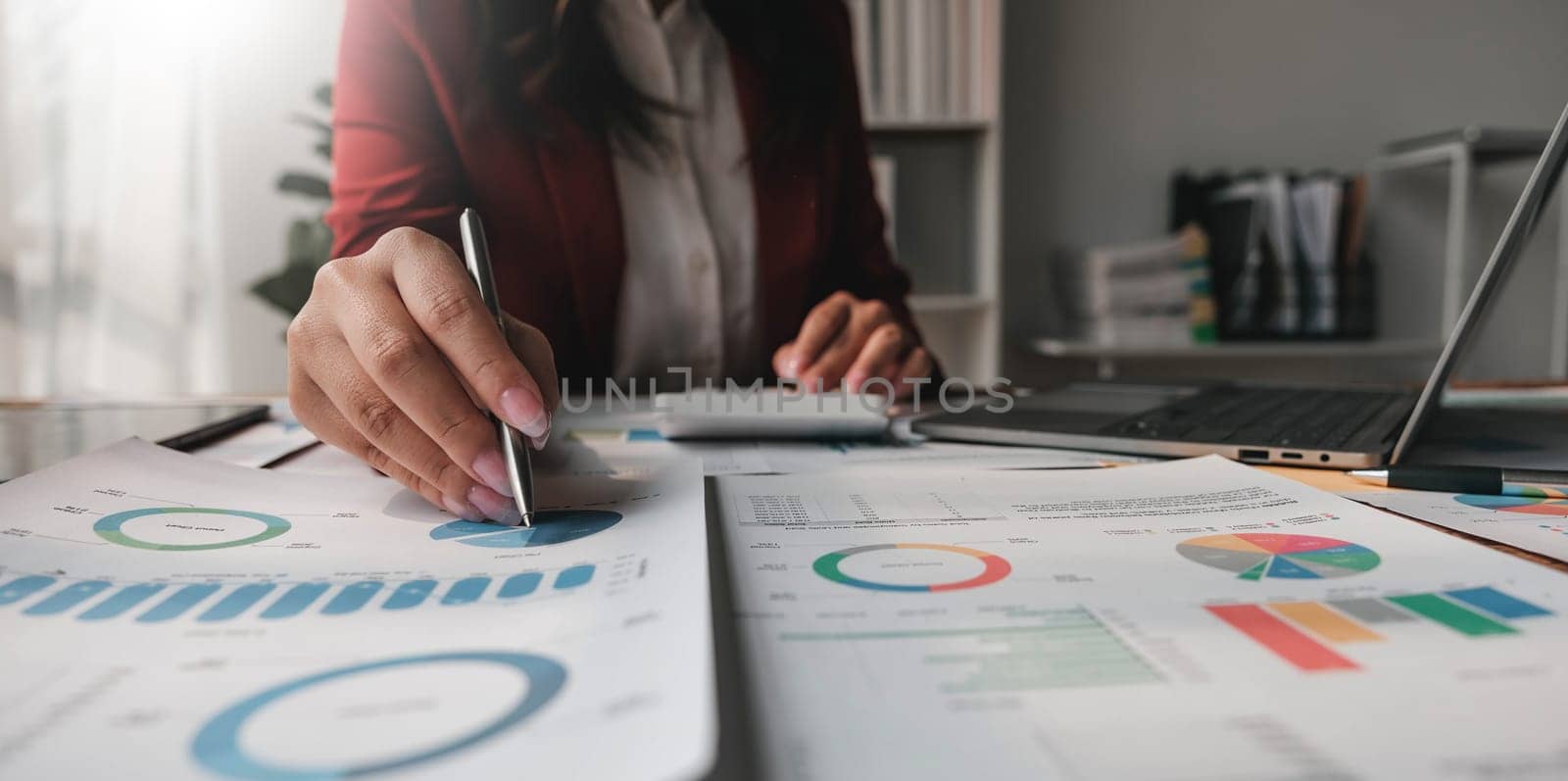 Close up Business woman using calculator and laptop for do math finance on wooden desk in office and business working background, tax, accounting, statistics and analytic research concept. by wichayada