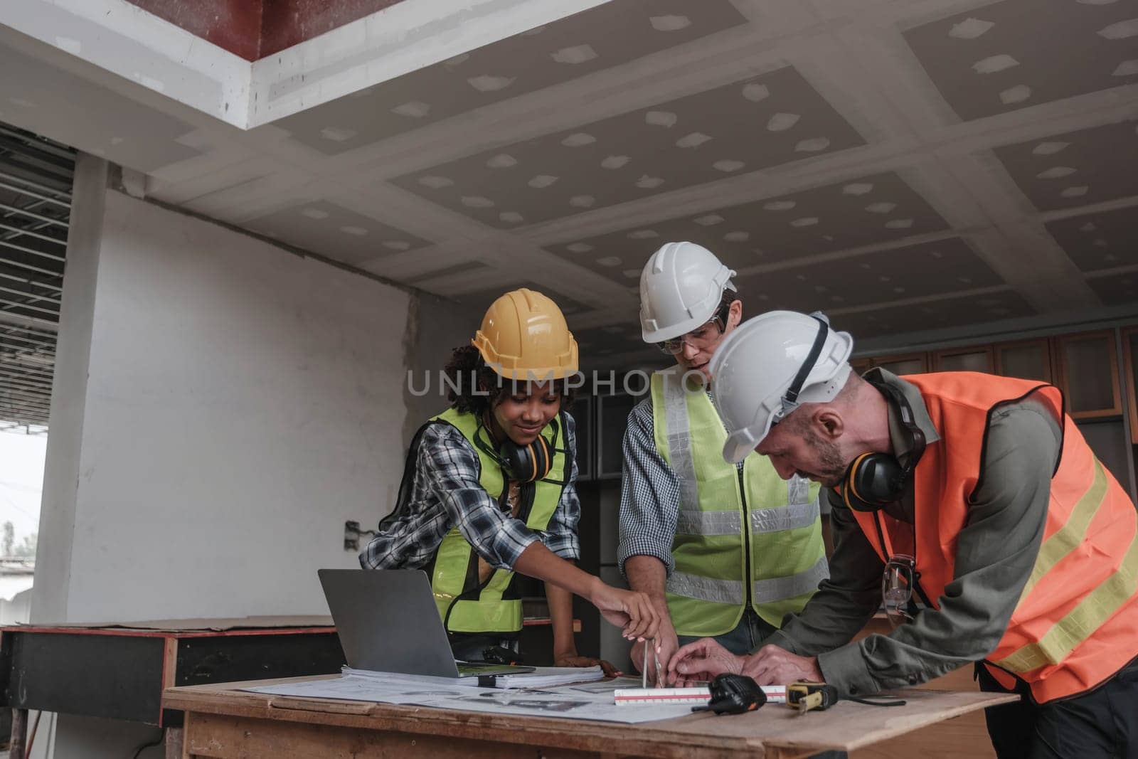 Civil engineer teams meeting working together wear worker helmets hardhat on construction site in modern city. Foreman industry project manager engineer teamwork. Asian industry professional team...