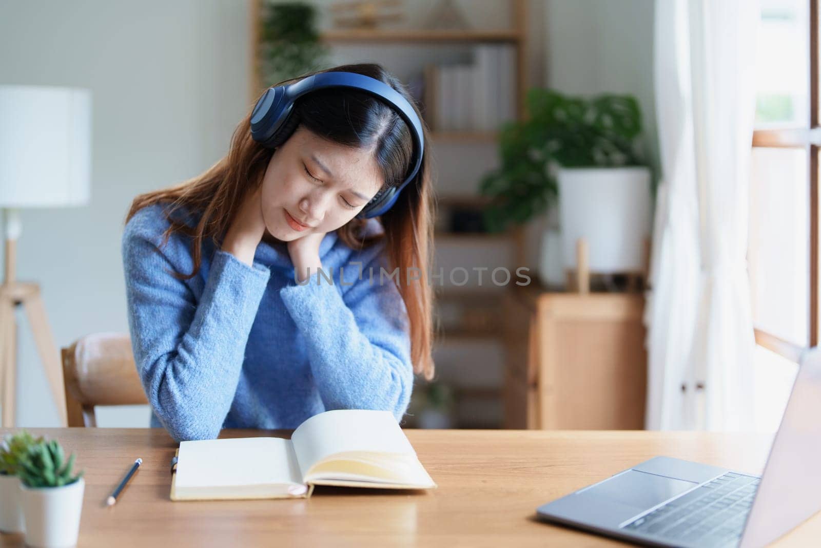 Portrait of young woman showing fatigue from studying online at home by Manastrong
