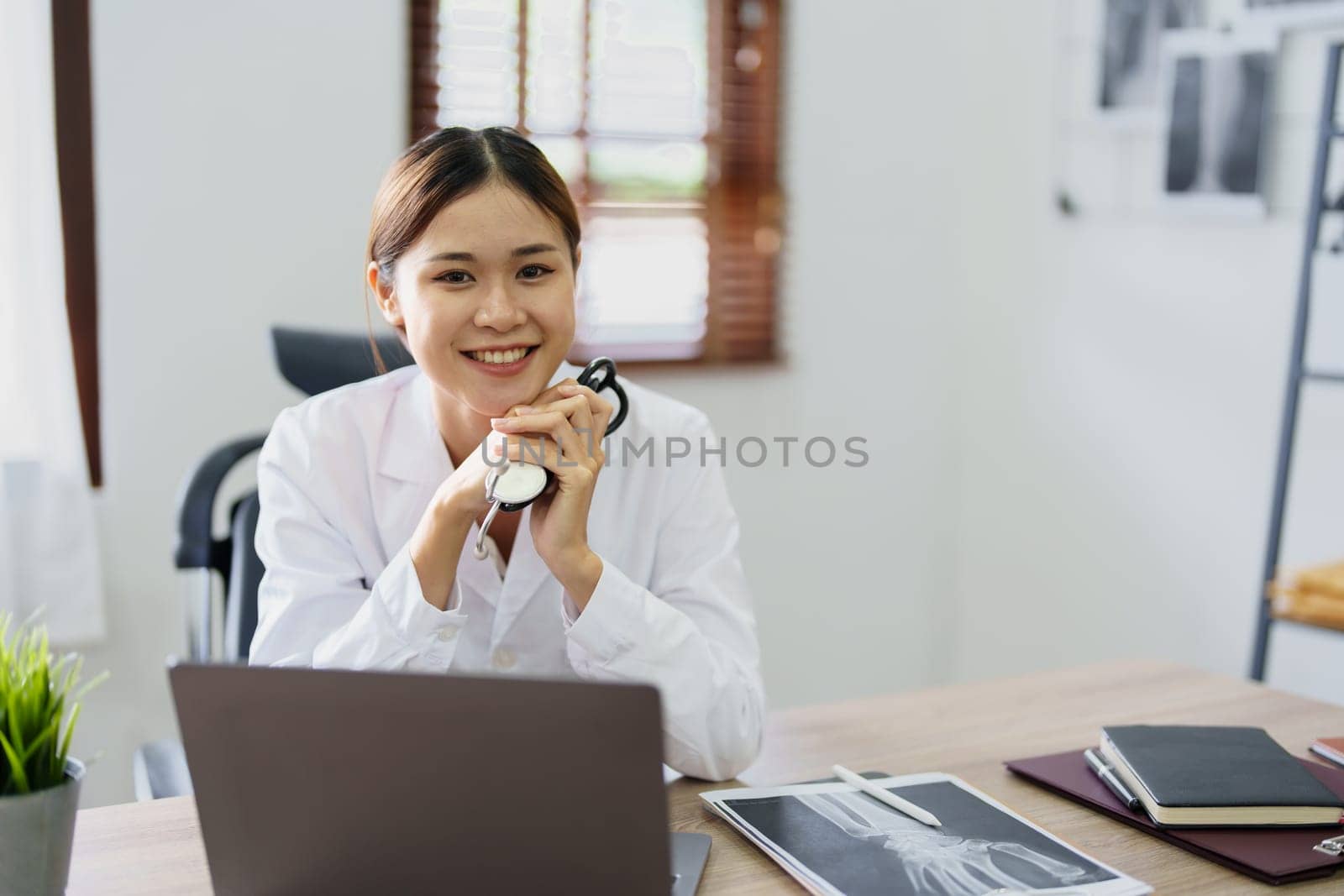 Portrait of an Asian doctor using a computer by Manastrong
