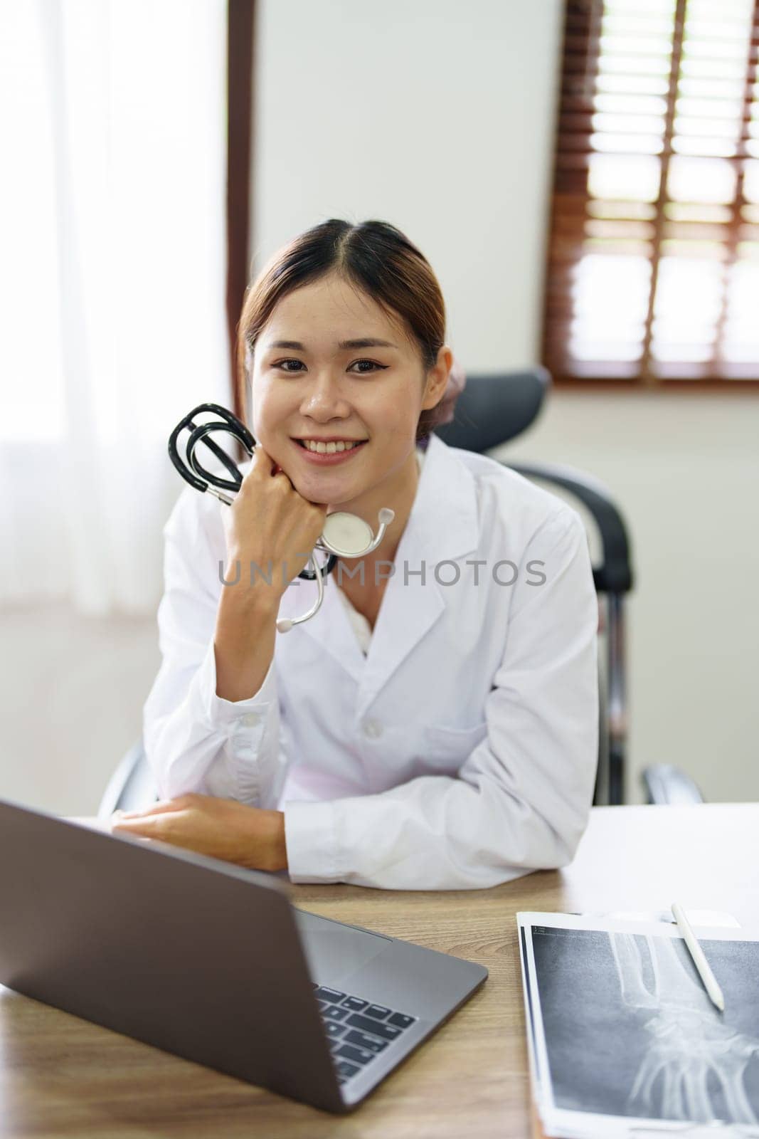 Portrait of an Asian doctor using a computer by Manastrong