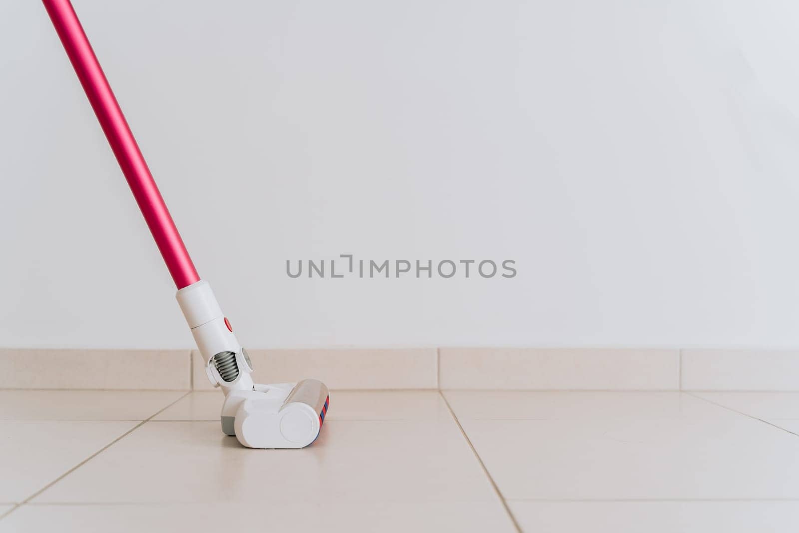 Closeup shot picture of vacuum cleaner brush head on tiled floor with white blank copy space in the background, no people.