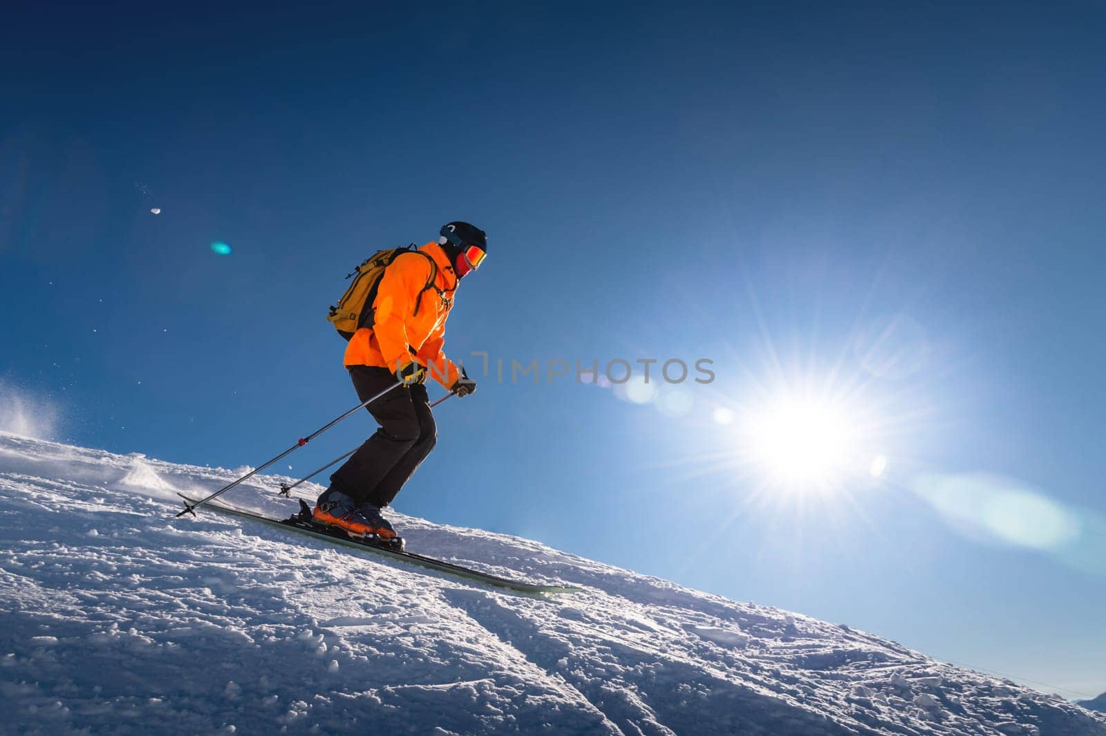 Professional skier athlete skiing at the top of a ski resort. Winter holidays and sports concept with adventure guy on the top of the mountain skiing down the slope.Warm bright sunny day by yanik88