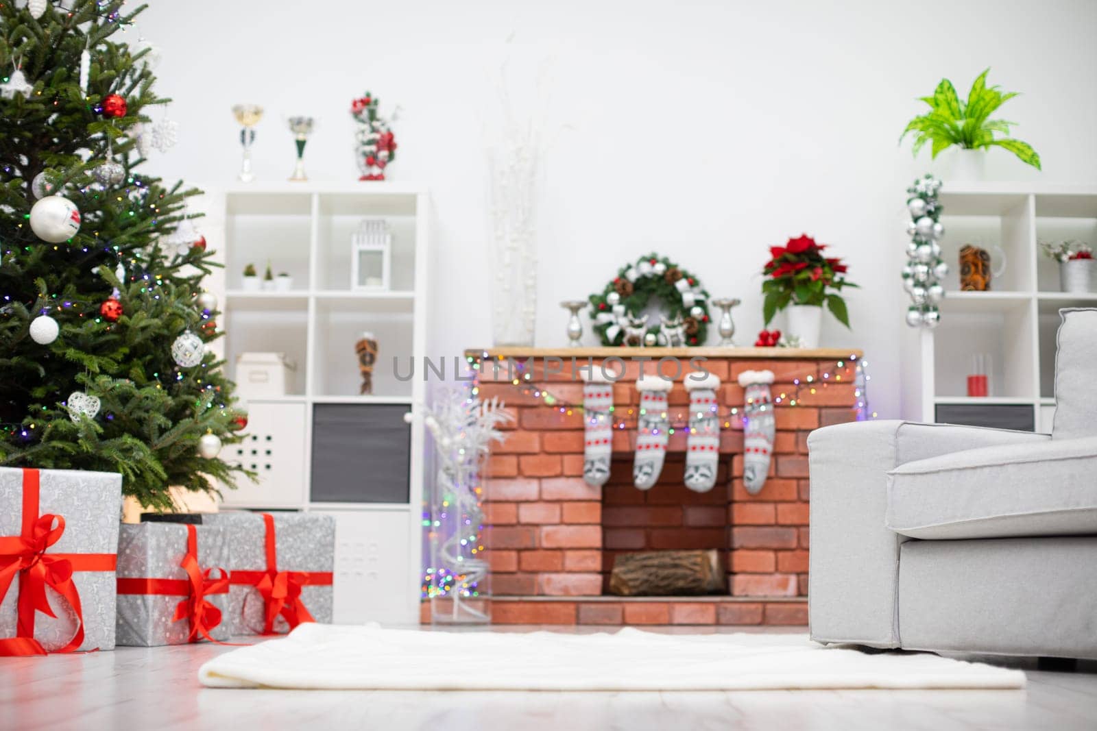 Decorated room with gifts under the Christmas tree. Fireplace with decorations in background.
