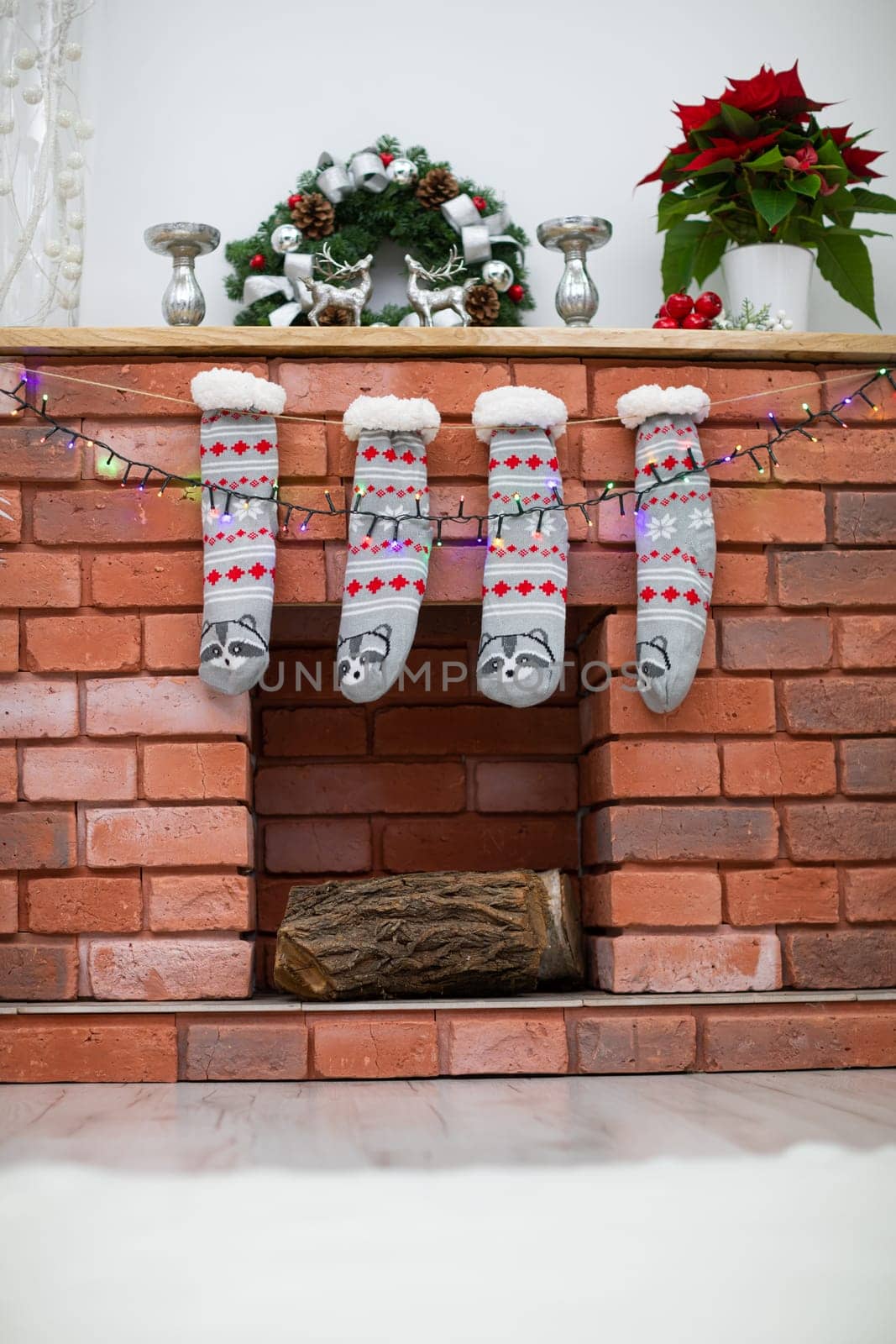 Decoration on the wooden shelf. Fireplace made of bricks and warm socks.