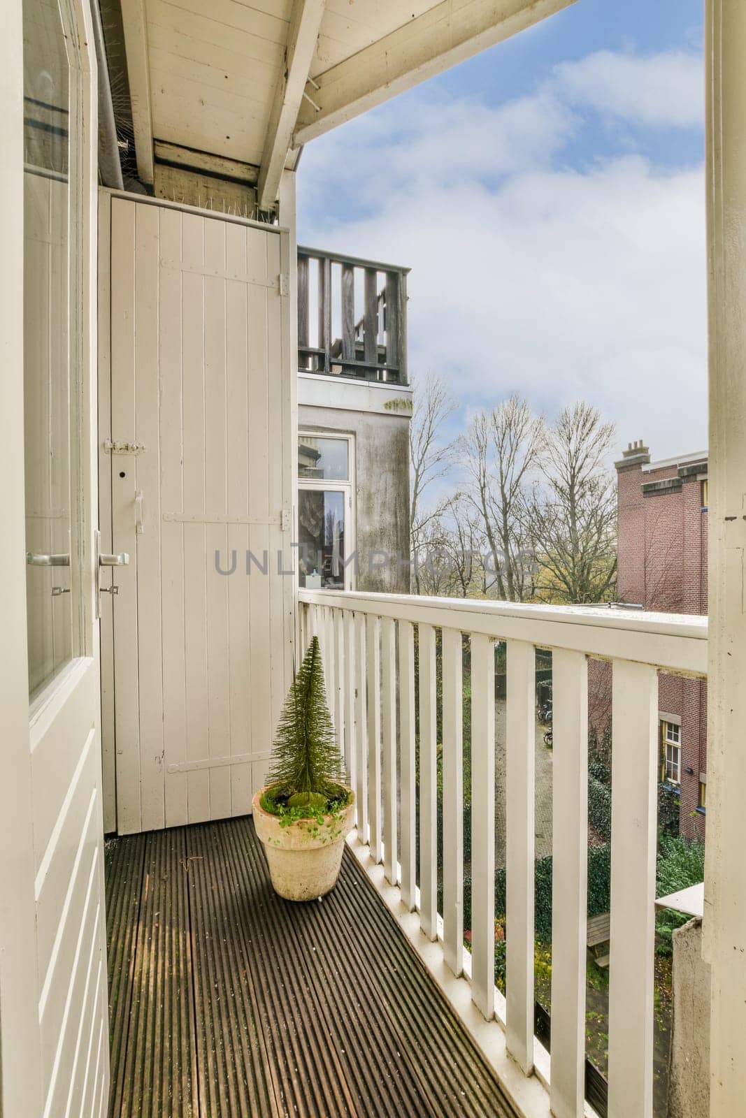 a balcony with wooden flooring and white railings on the side of the house, looking out onto the street