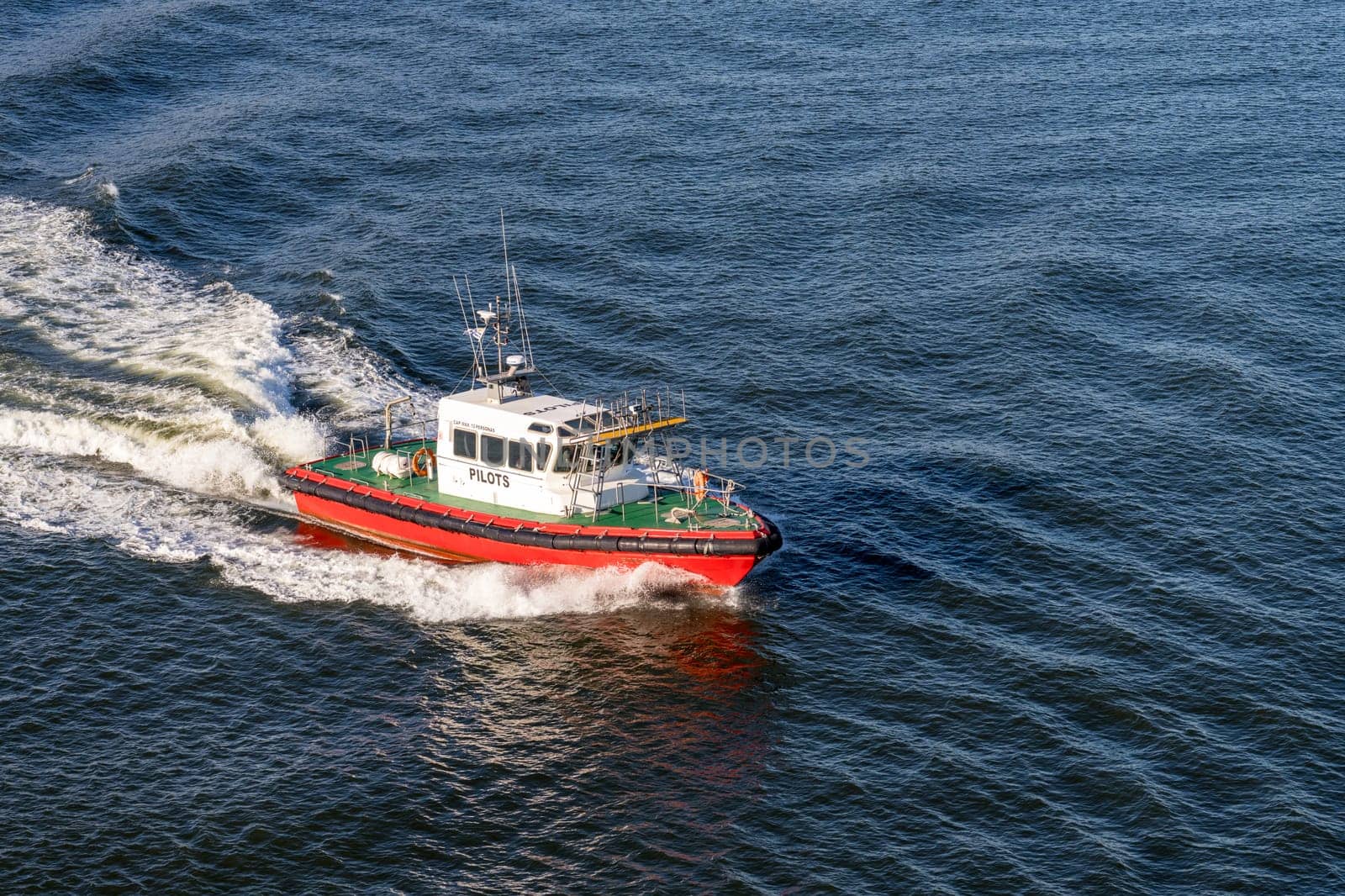 Red pilot boat speeding back to shore after escorting ship from harbor