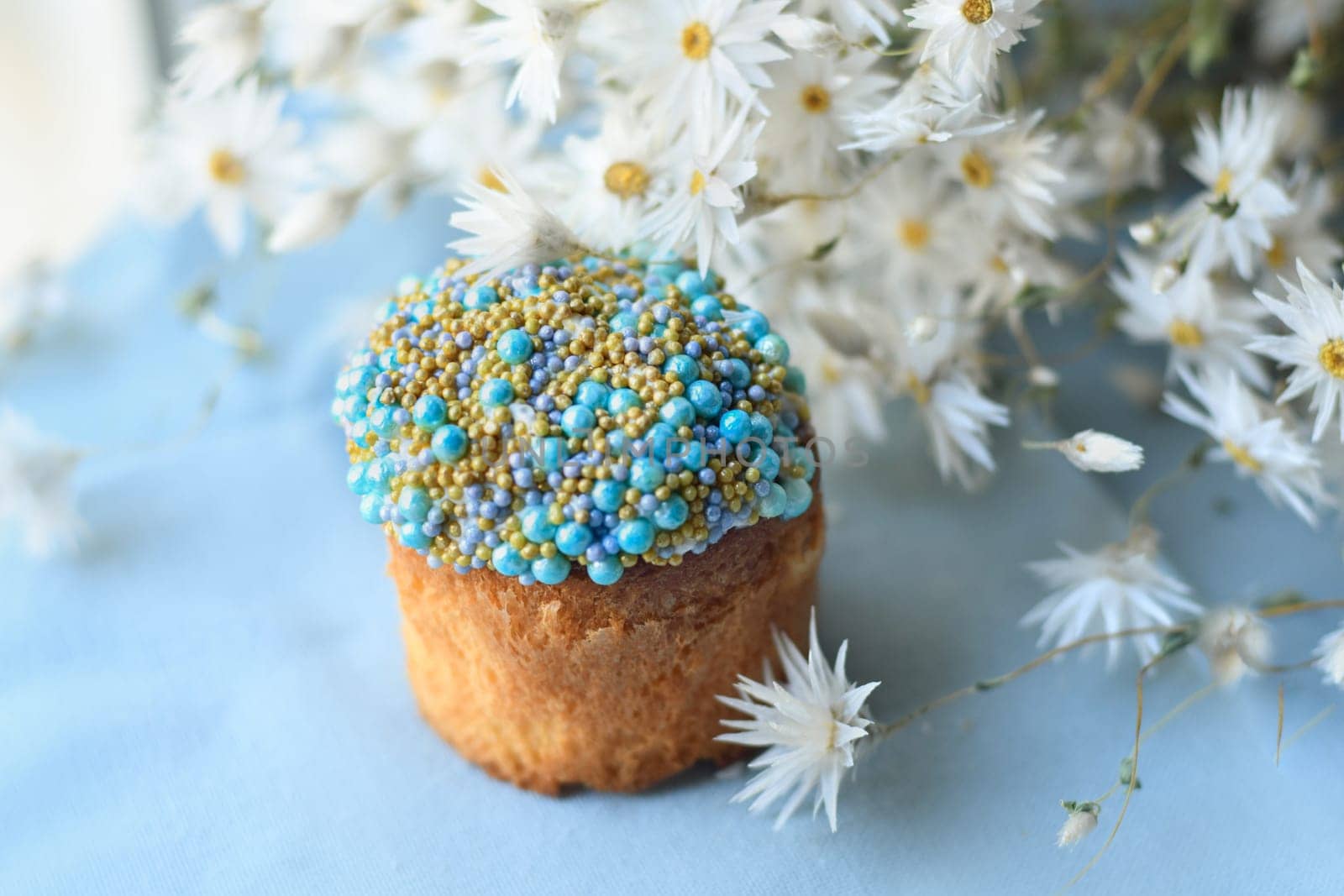 Orthodox Easter cake decorated with beads and daisies in the blue background