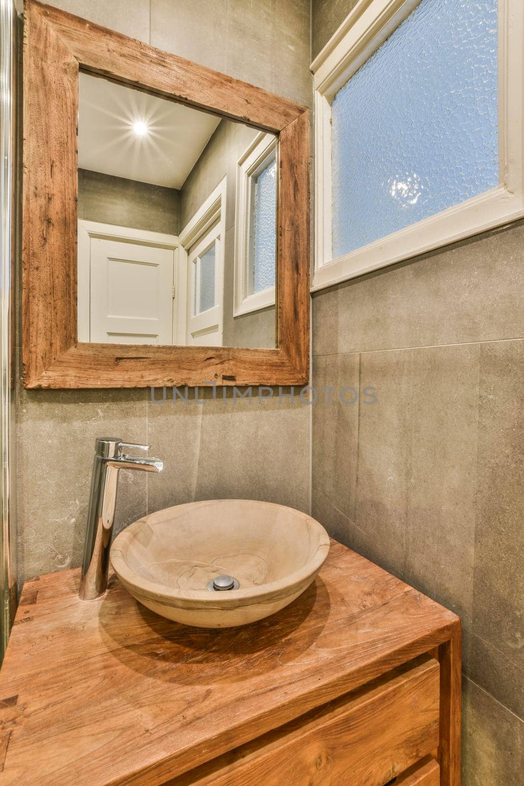 a bathroom with a wooden sink and mirror in the corner on the wall above it is a window that looks out to the outside