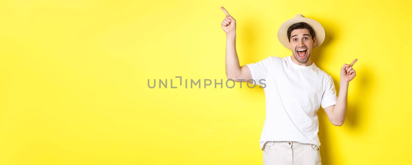 Concept of tourism and lifestyle. Happy tourist dancing and pointing fingers sideways, showing vacation variants, yellow background by Benzoix