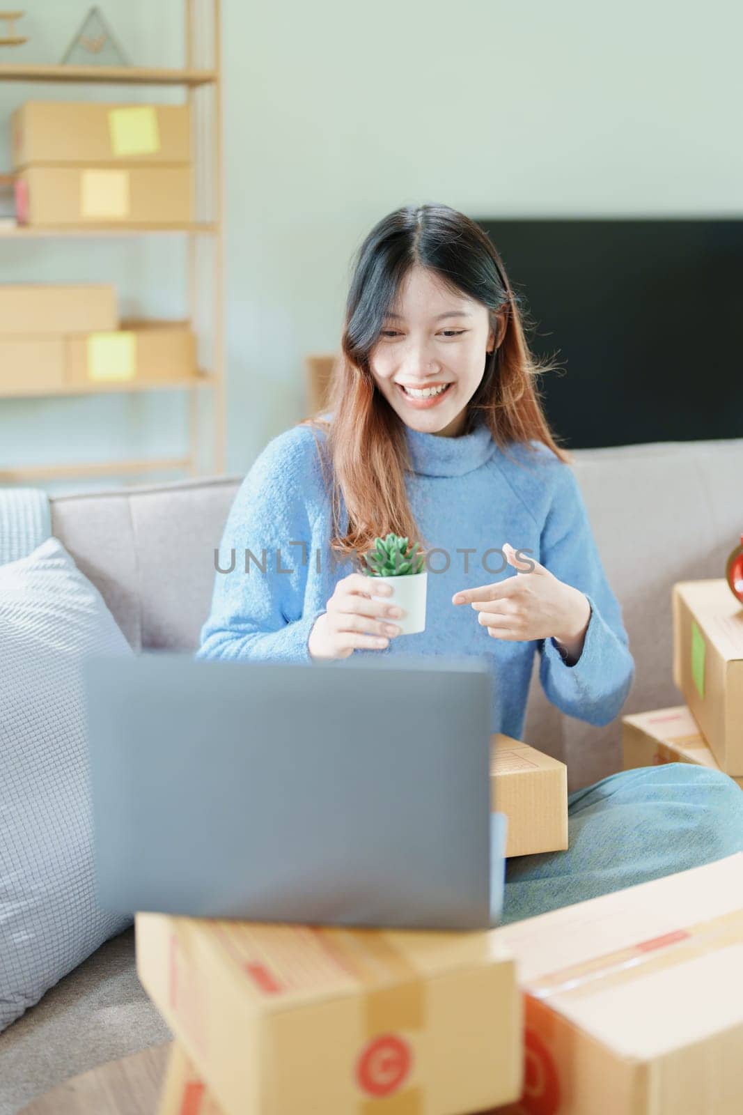 Starting small business entrepreneur of independent Asian woman smiling using computer laptop with cheerful success of online marketing package box items and SME delivery concept.