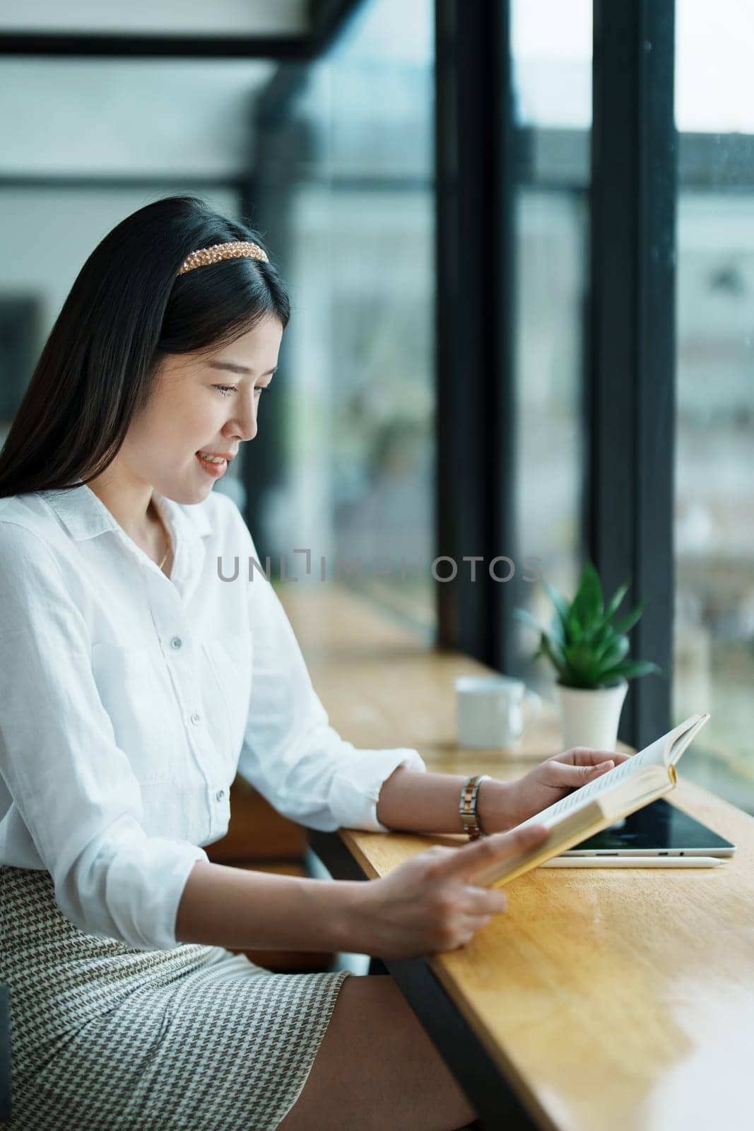 Portrait of a beautiful Asian female employee reading a book during her lunch break.
